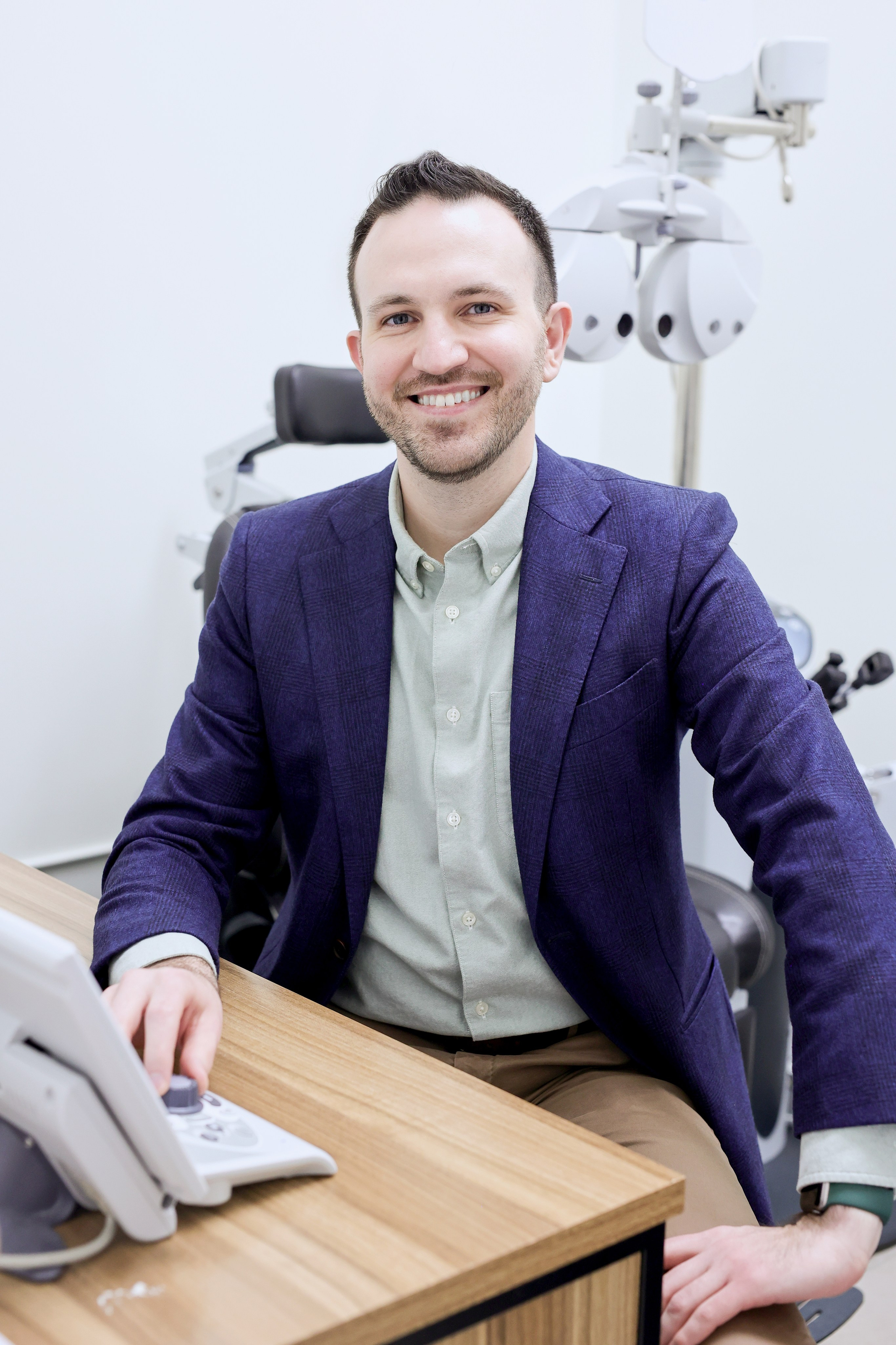 headshot of male optometrist in his office wearing blue blazer 