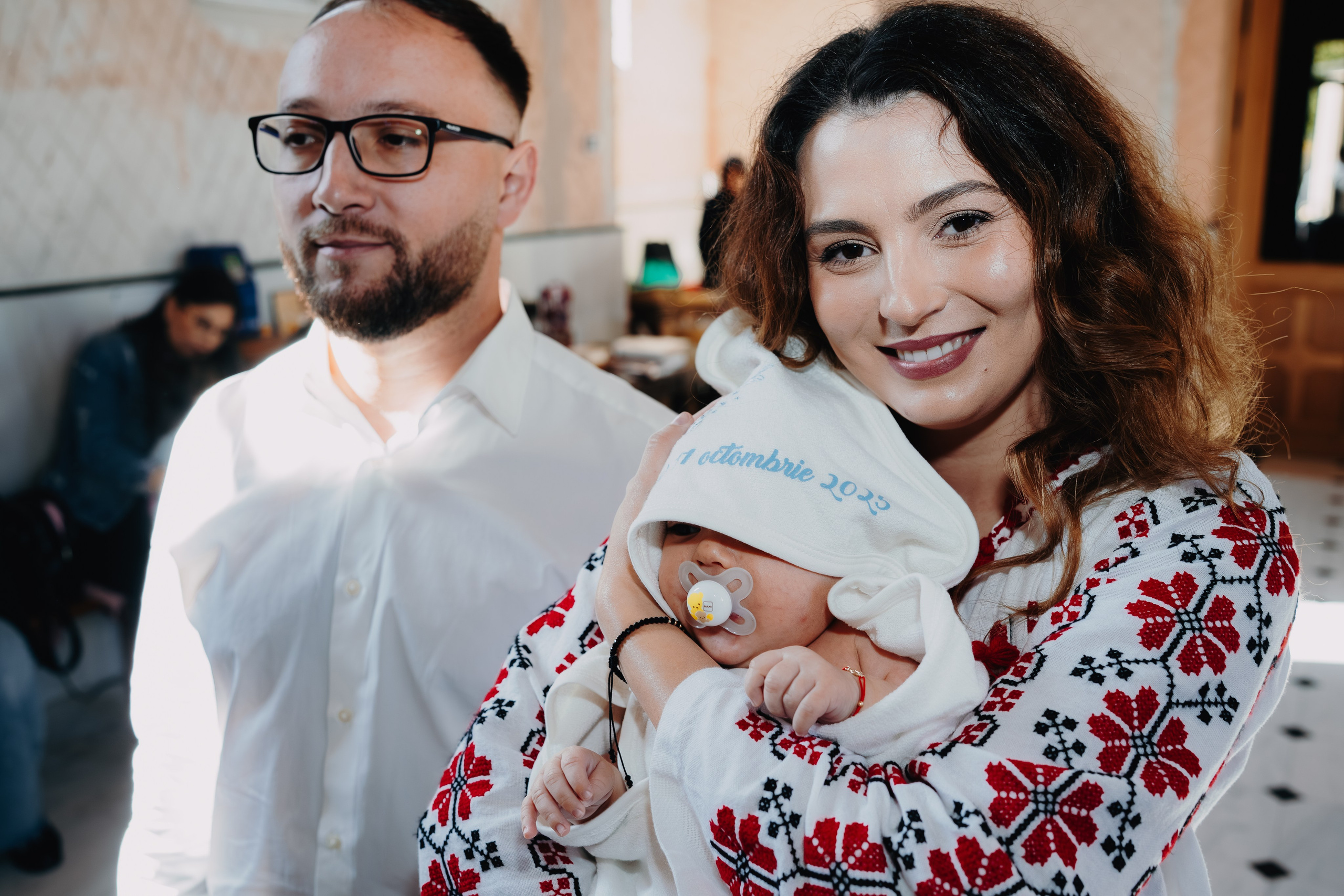 Arthur Mihail, înfășat în prosopul alb, este ținut cu grijă în brațele nașei în momentul solemn de așteptare imediat dinaintea botezului, în Catedrala din Bârlad.