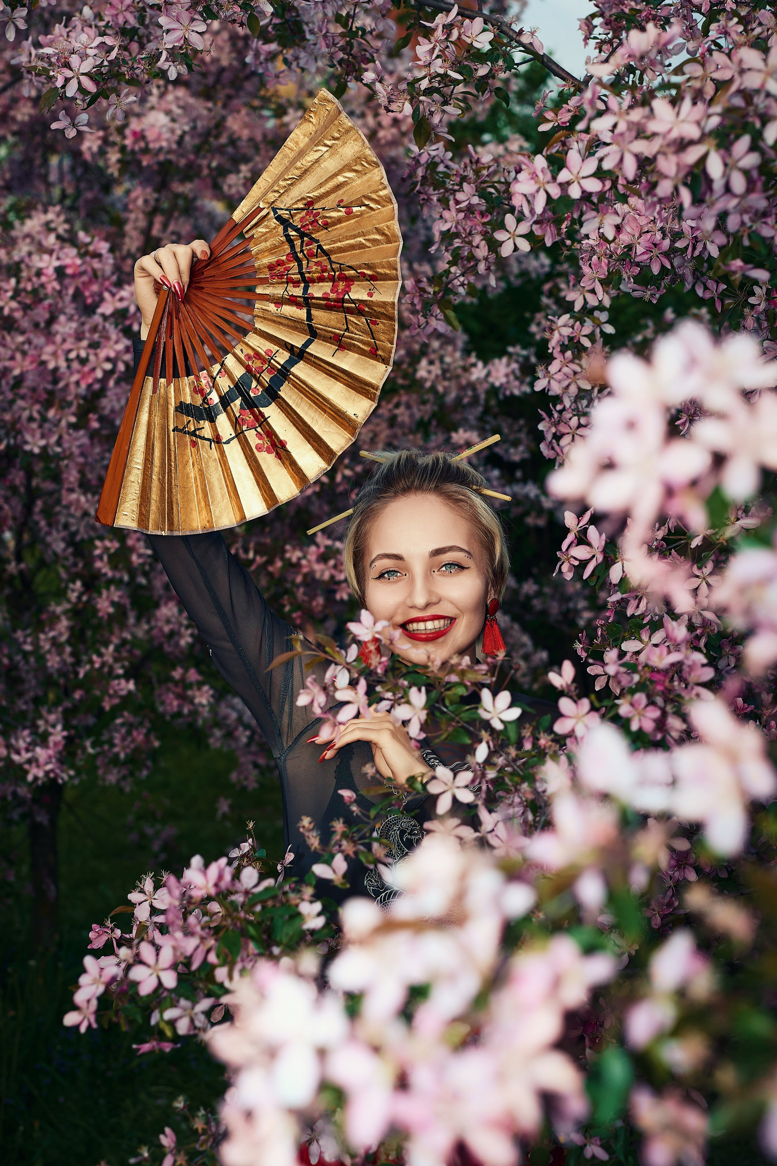 Уличная фотосесия красивая девушка с веером в цветах яблони сакуры