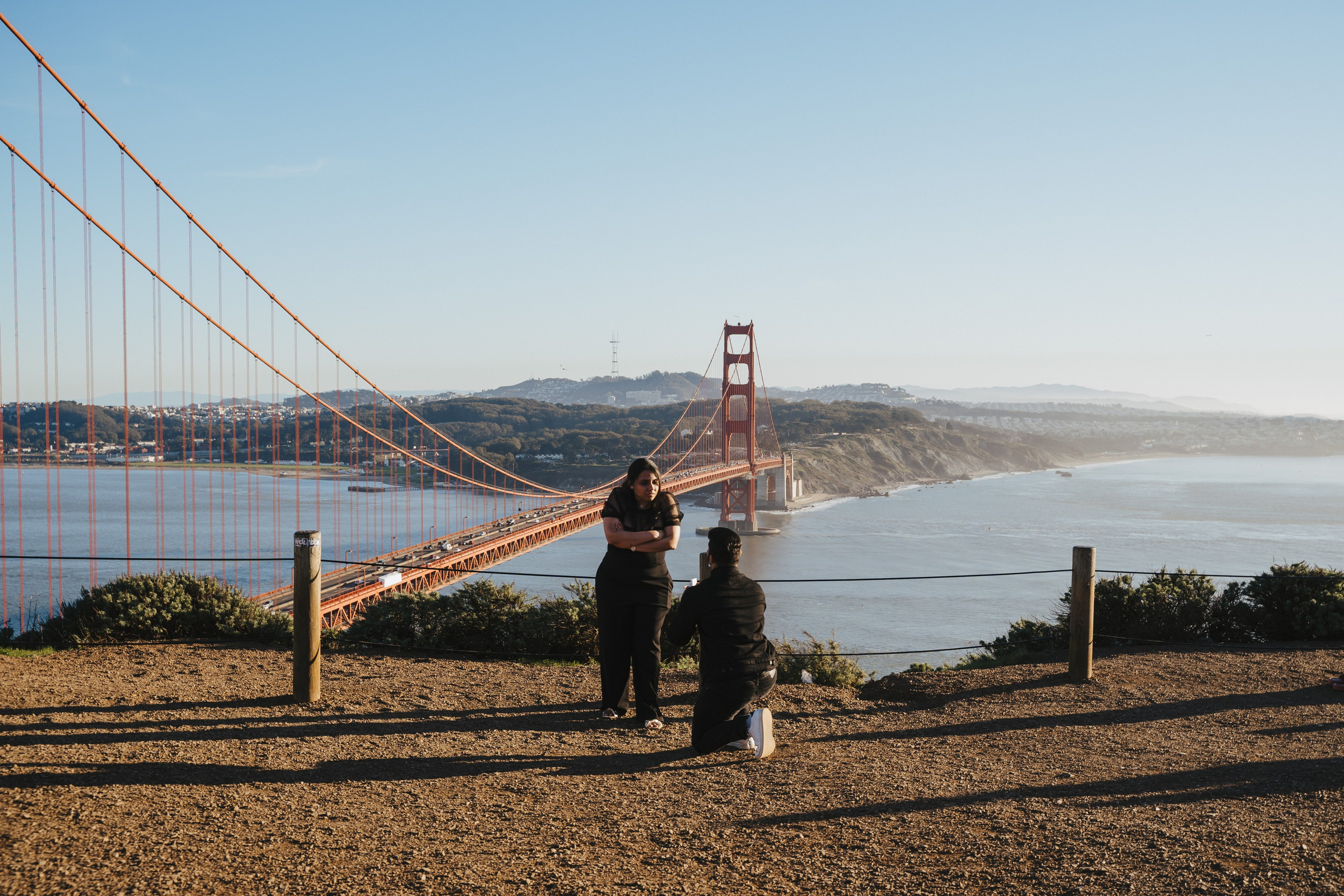 Proposal.  Overlooking the golden San Franisco Bridge sunset with a couple. Photographer Video. 