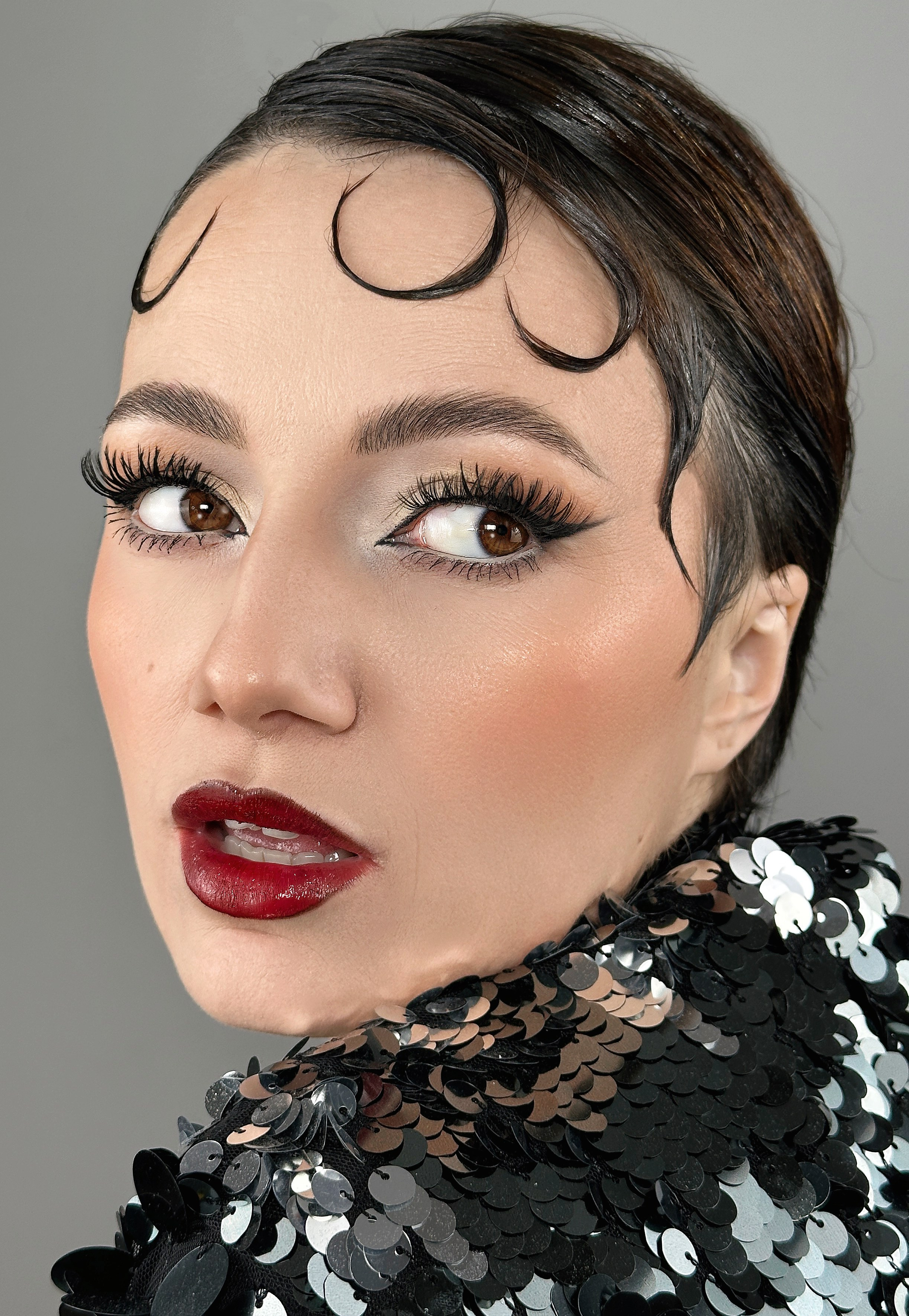 „Machiaj retro glam iconic inspirat din anii '50, cu eyeliner cat-eye, buze roșii intense și ten impecabil. Un look clasic și elegant pentru evenimente speciale.”