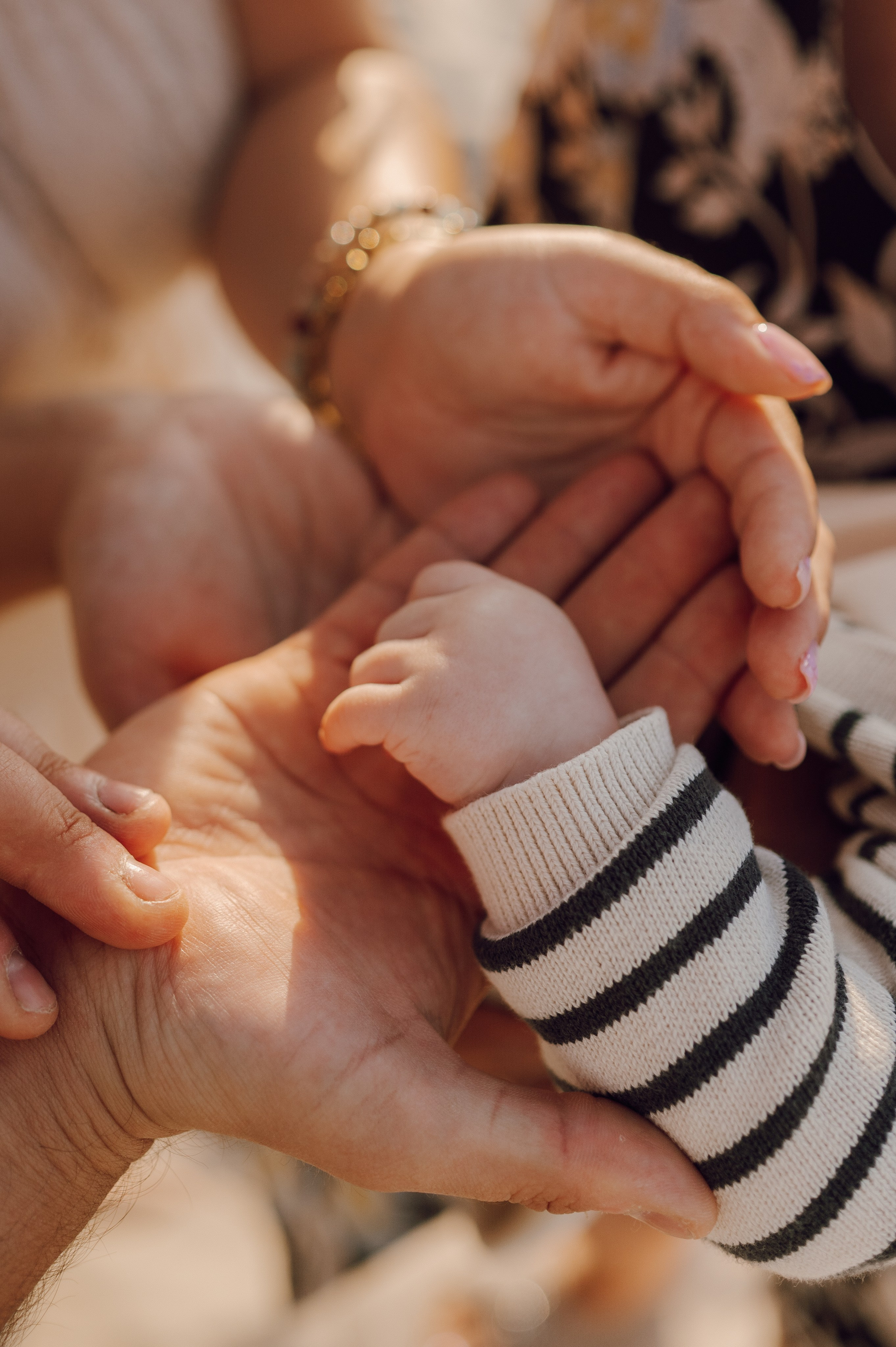 Noworodek trzymany w dłoniach rodziców – wzruszająca sesja lifestyle, fotografia noworodkowa Poznań.