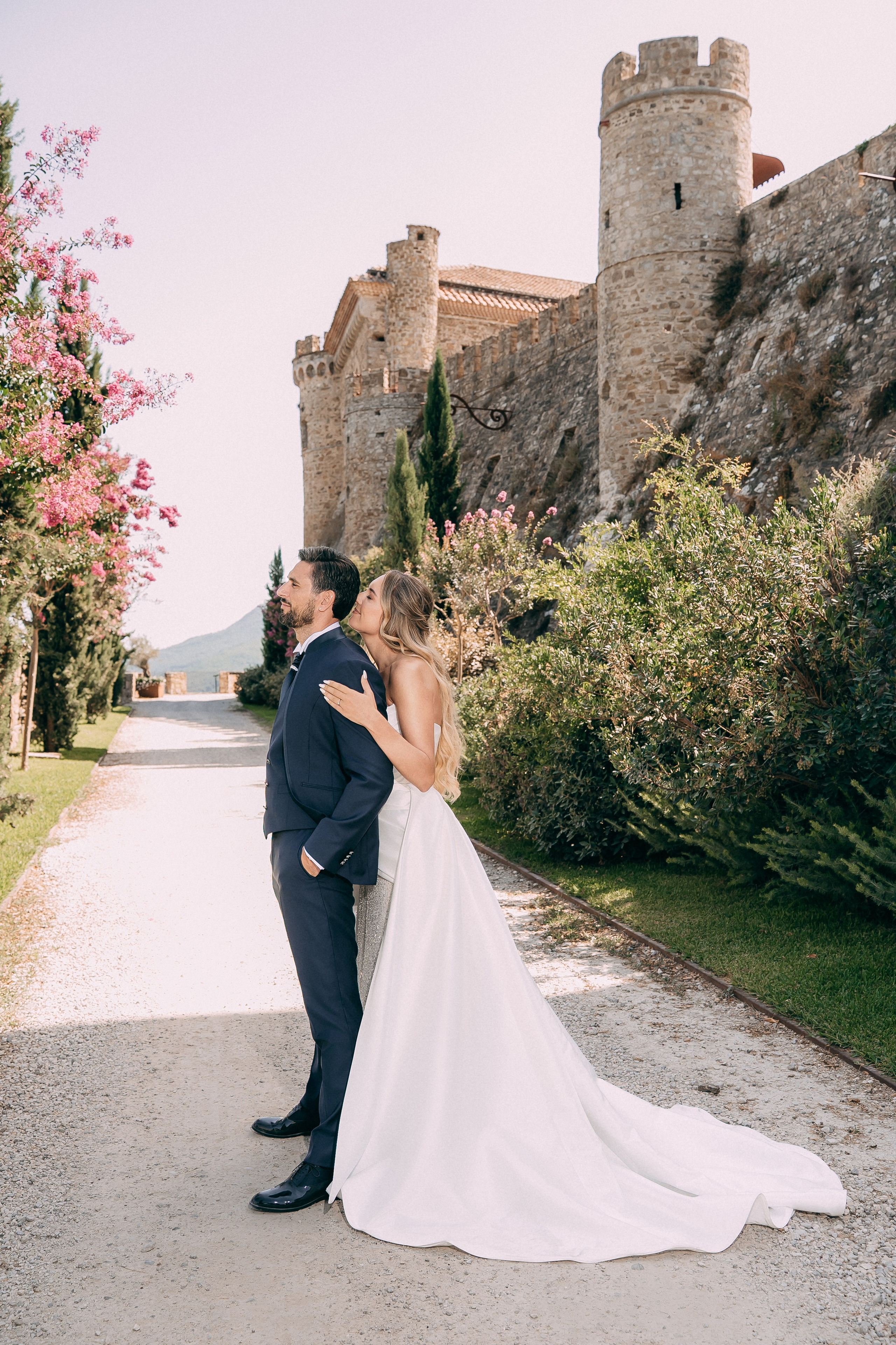 Bride and groom kissing in front of the medieval towers of Rocca Cilento