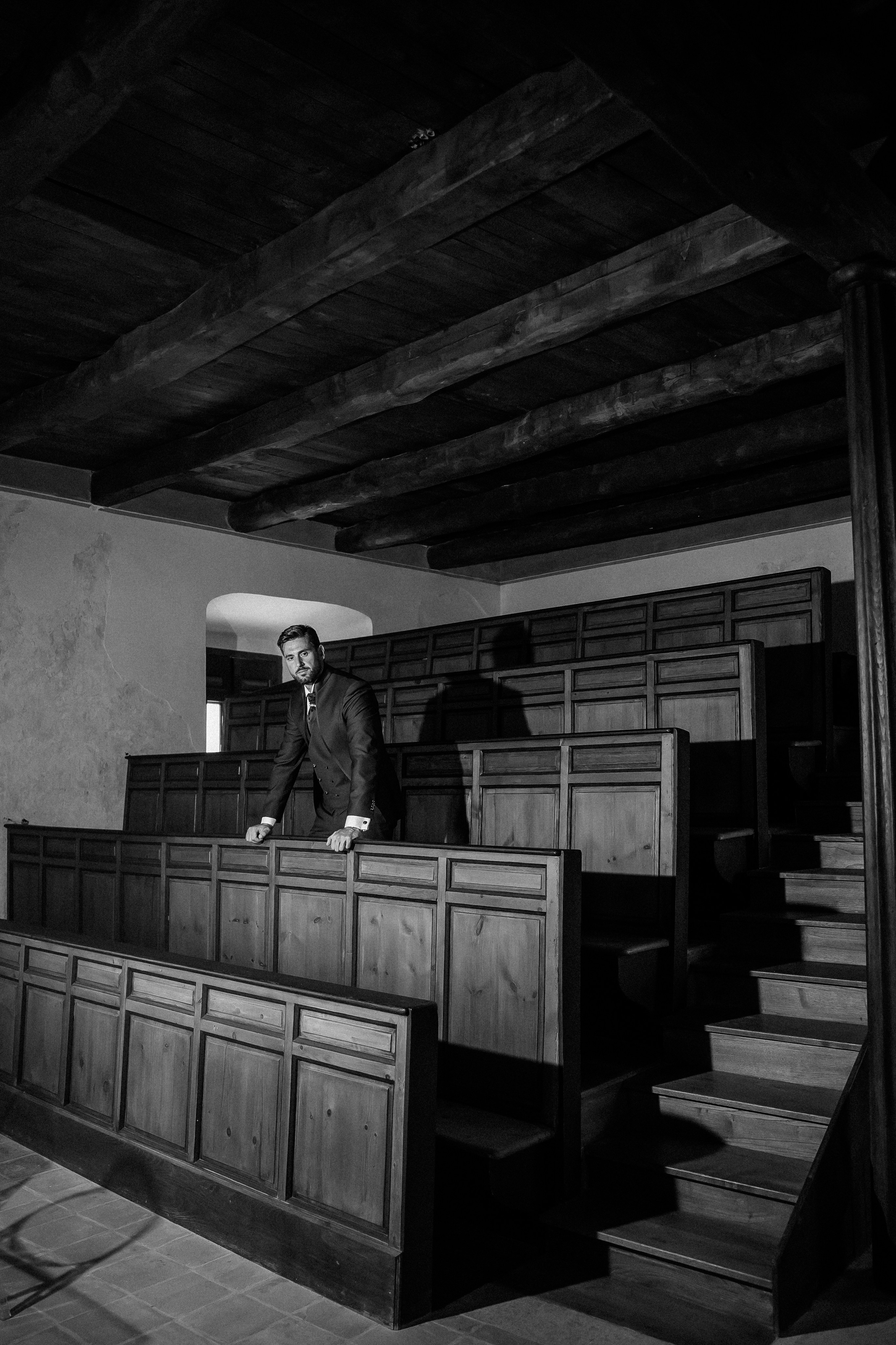 Black and white portrait of the groom on the stone staircase of the castle