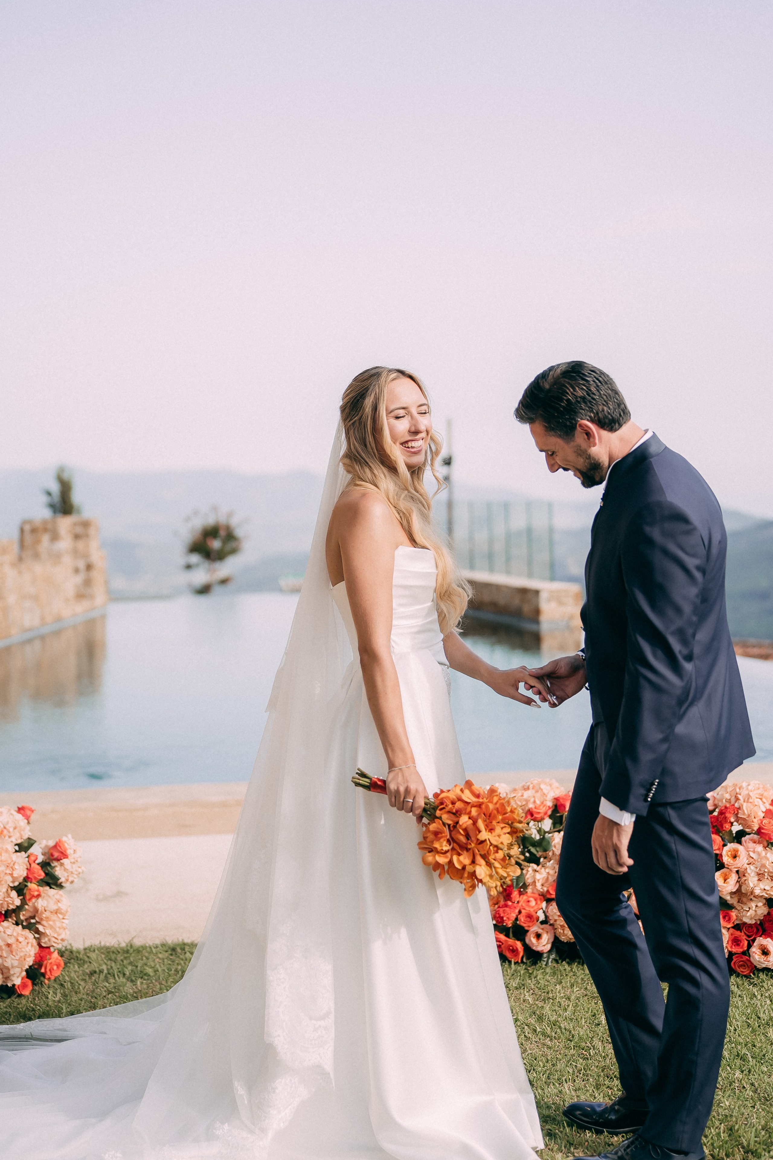 Bride and groom holding hands during the ceremony by the pool