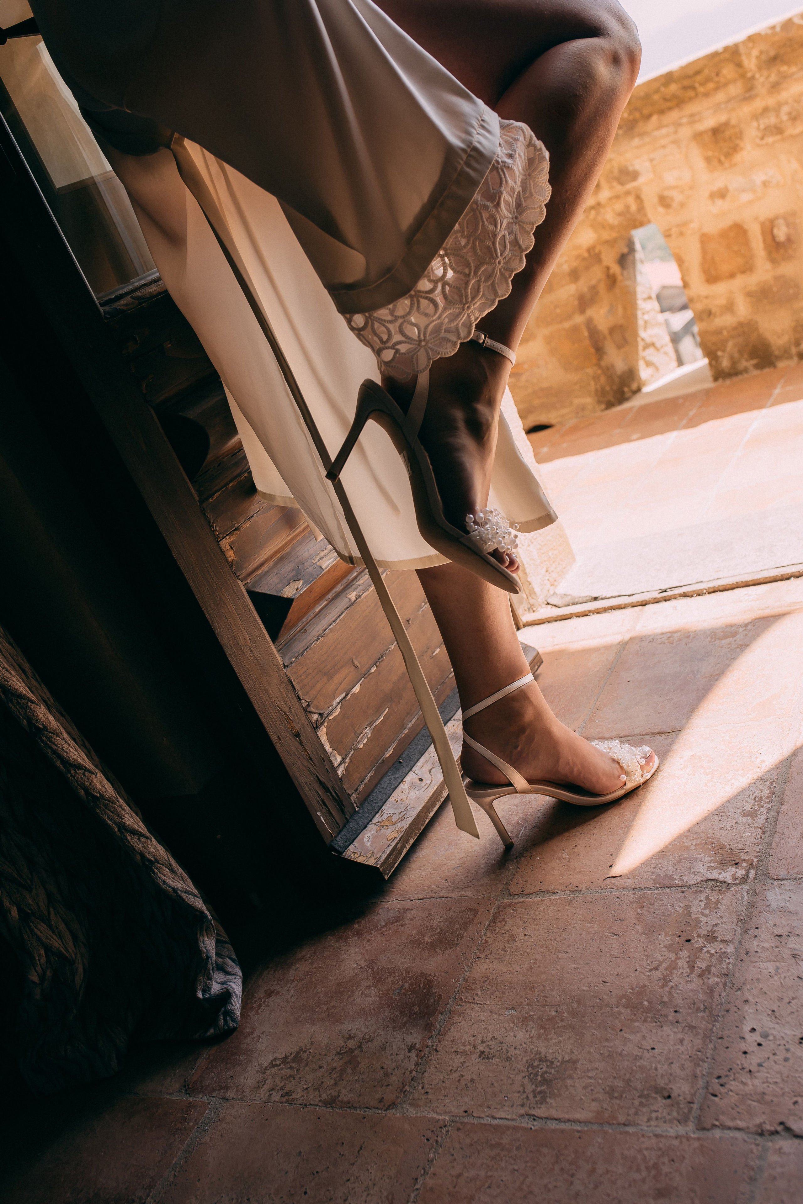 Detail of the bride's satin heels and dress on the castle terrace
