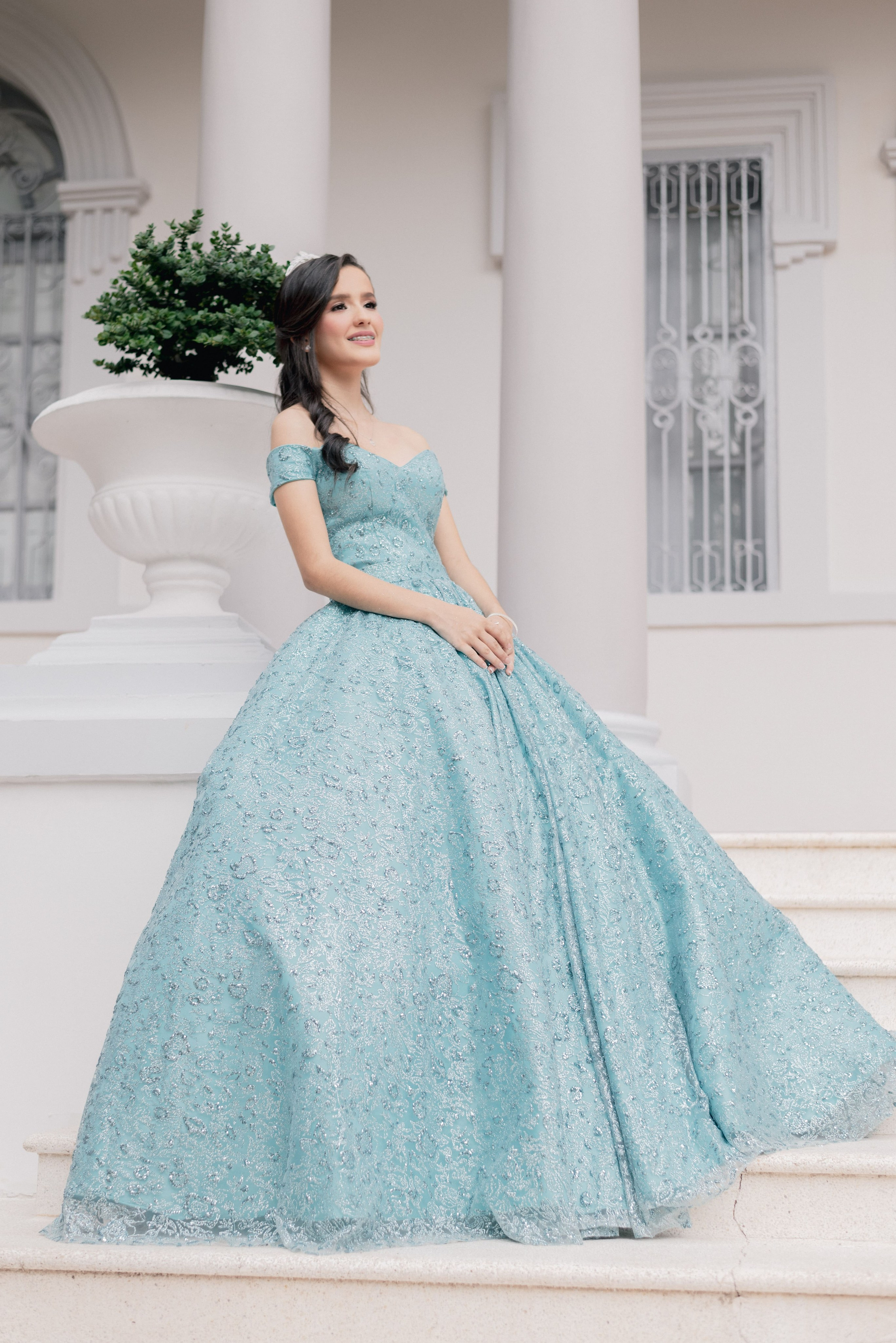 Quinceañera princesa sesión de fotos profesional en Barranquilla, retrato elegante de joven con vestido azul en columnas blancas, fotografía de ensueño estilo lujo