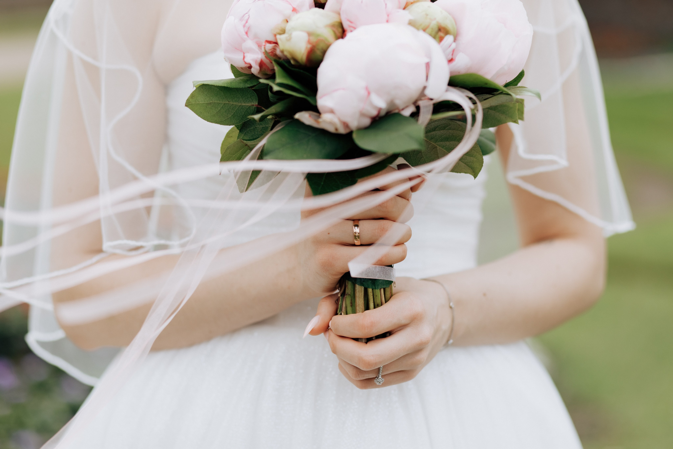 Hochzeitsstrauß aus rosa Pfingstrosen in den Händen der Braut.