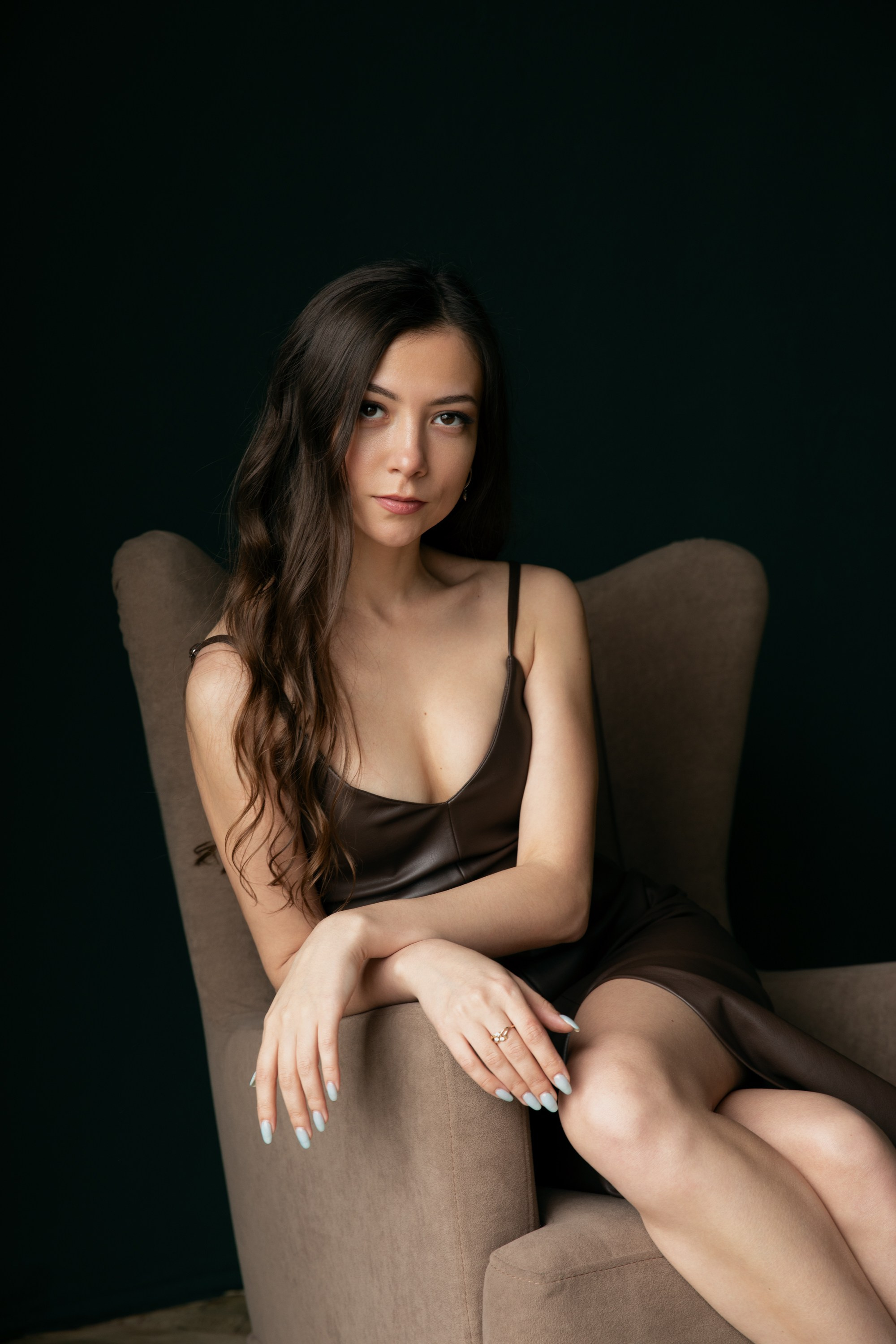 Elegante Frau im Lederkleid sitzt im braunen Sessel