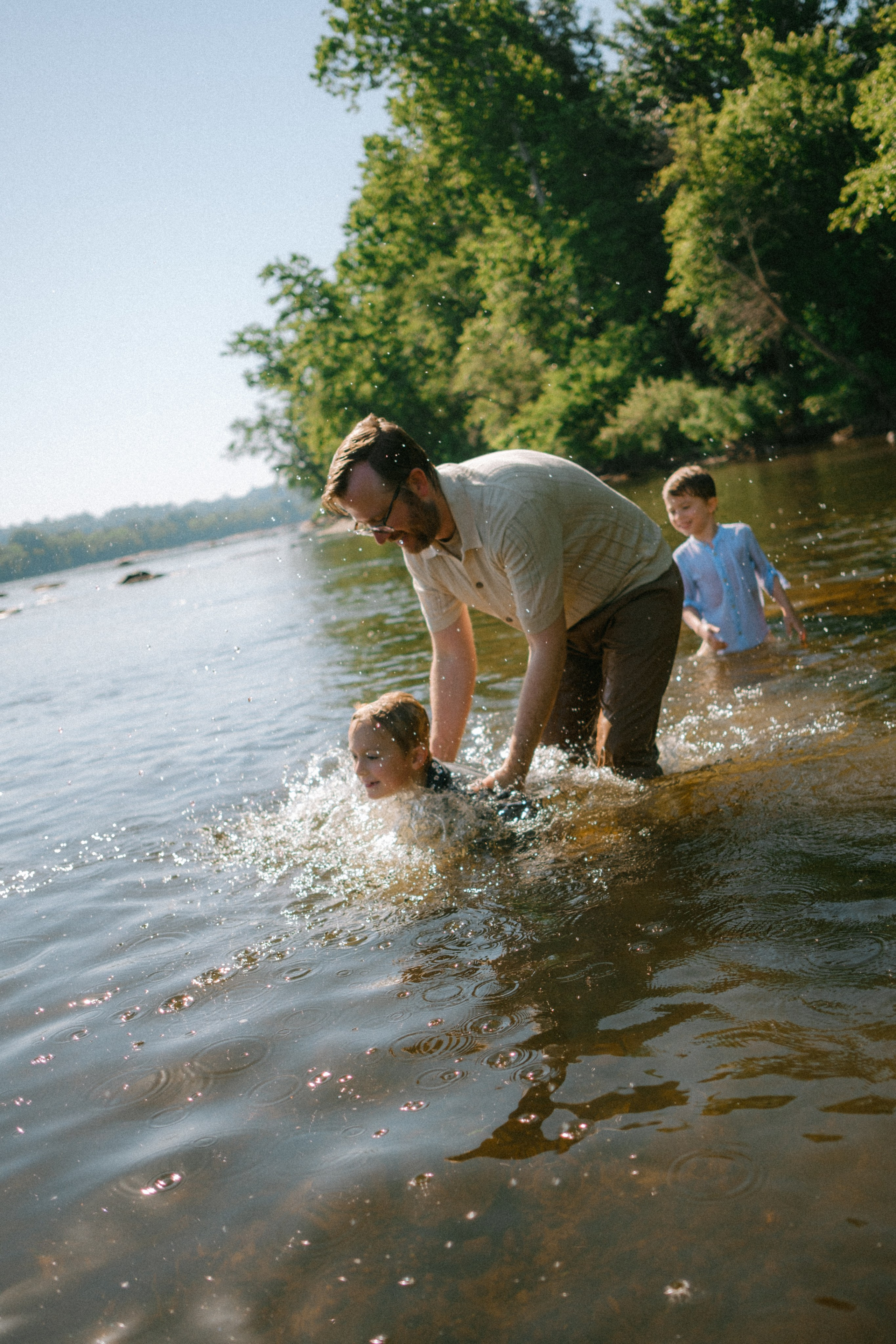 Documentary family photographer capturing candid, unposed moments of kids splashing in the James River water