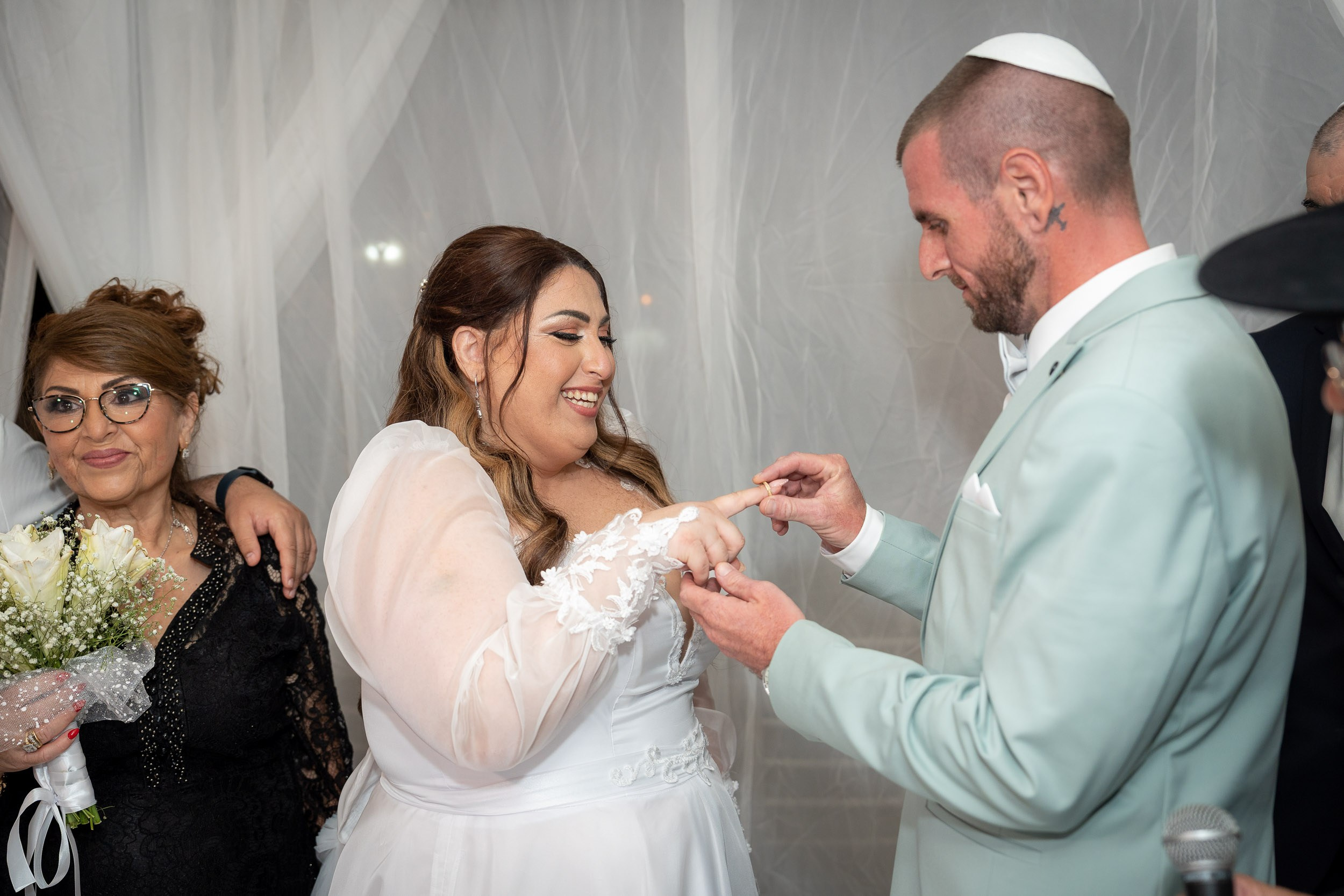 Matan places the wedding ring on Ella’s finger beneath the chuppah