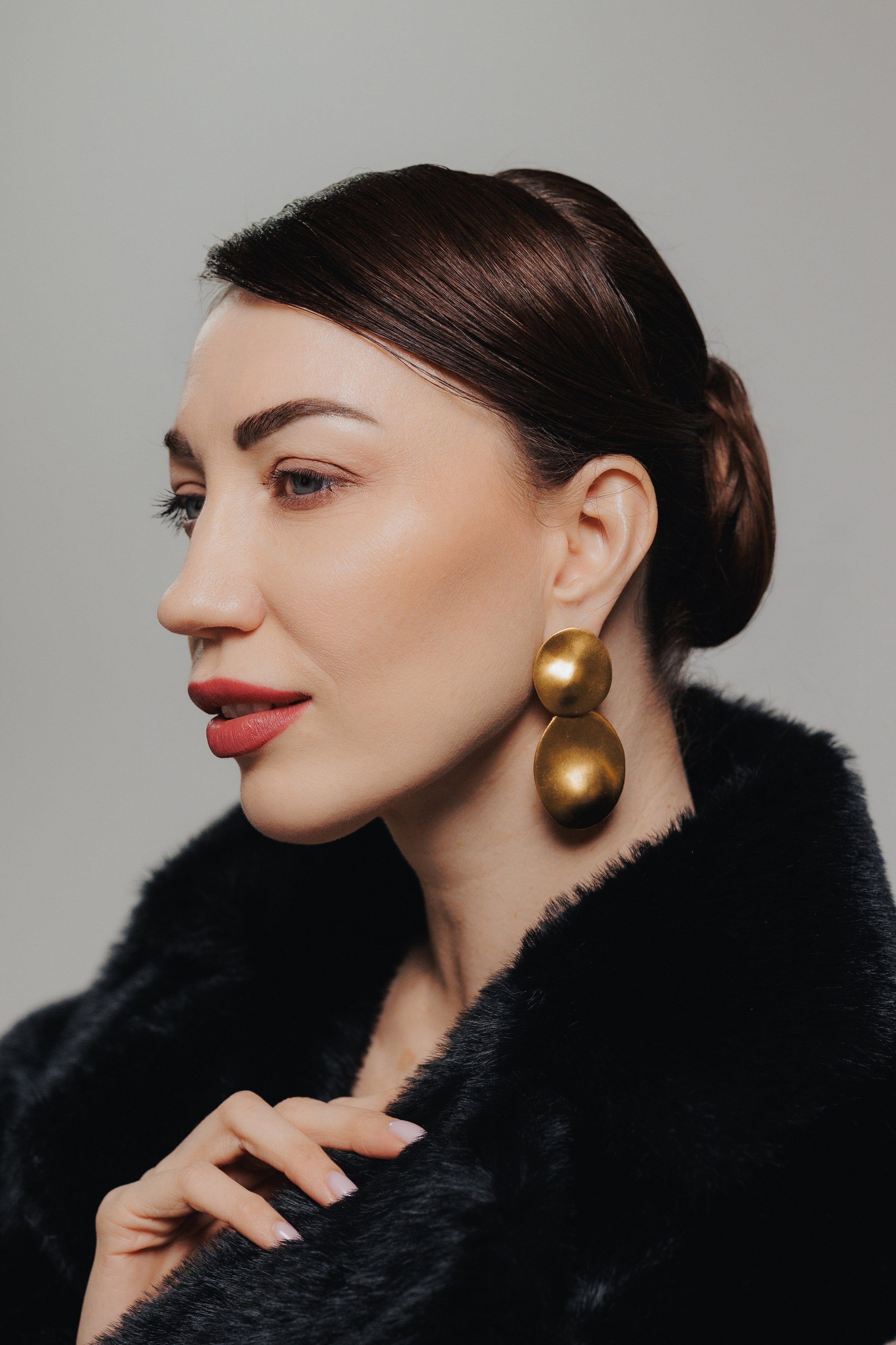 Editorial close-up portrait of a woman in a black fur coat with statement earrings and sleek hairstyle, photographed in Leipzig, Germany. Редакционный крупный портрет девушки в чёрной шубе с выразительными серьгами и гладкой причёской, снятый в Лейпциге, Германия.
