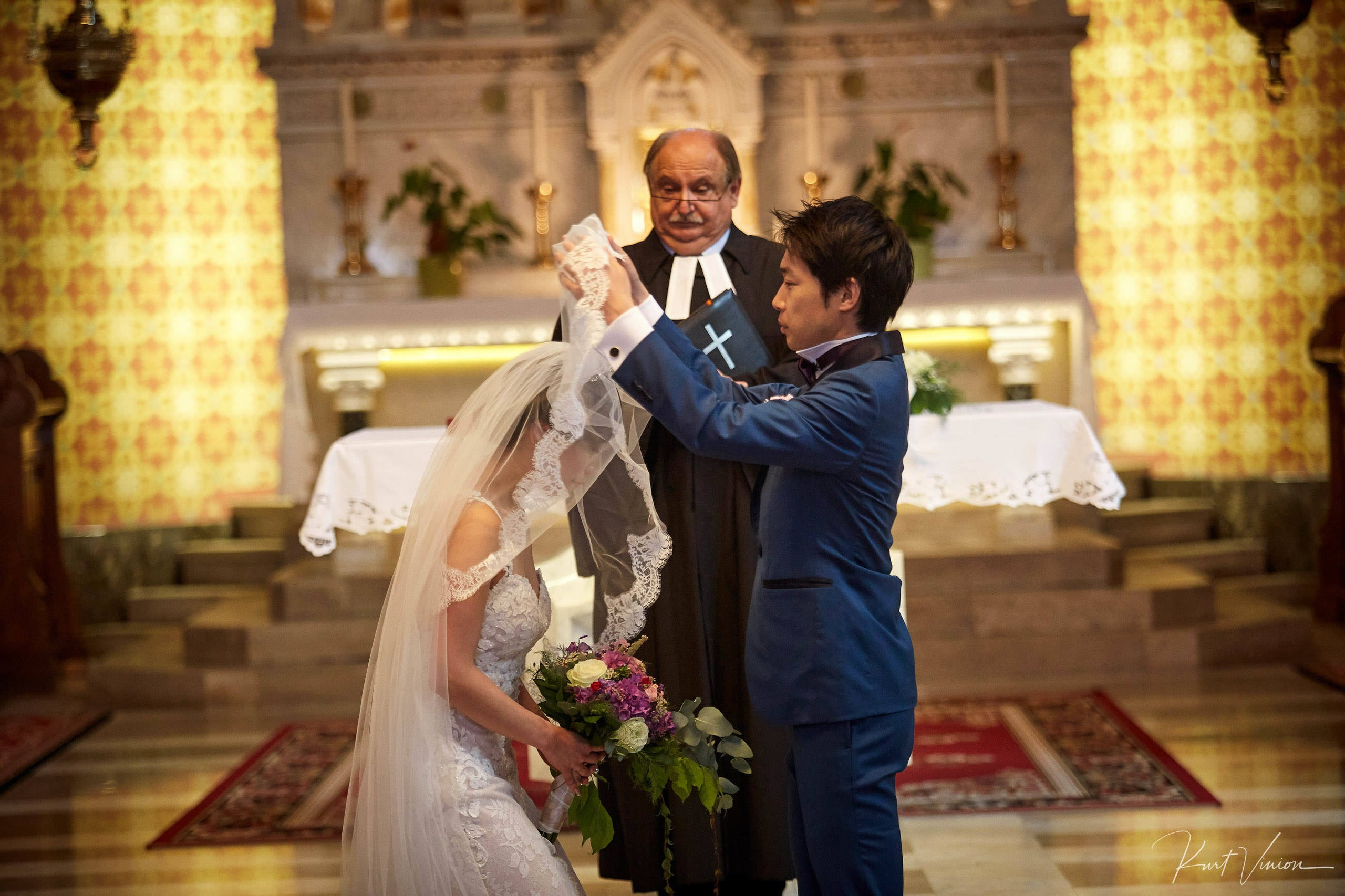 Groom lifting bride's veil during intimate Bled civil ceremony.