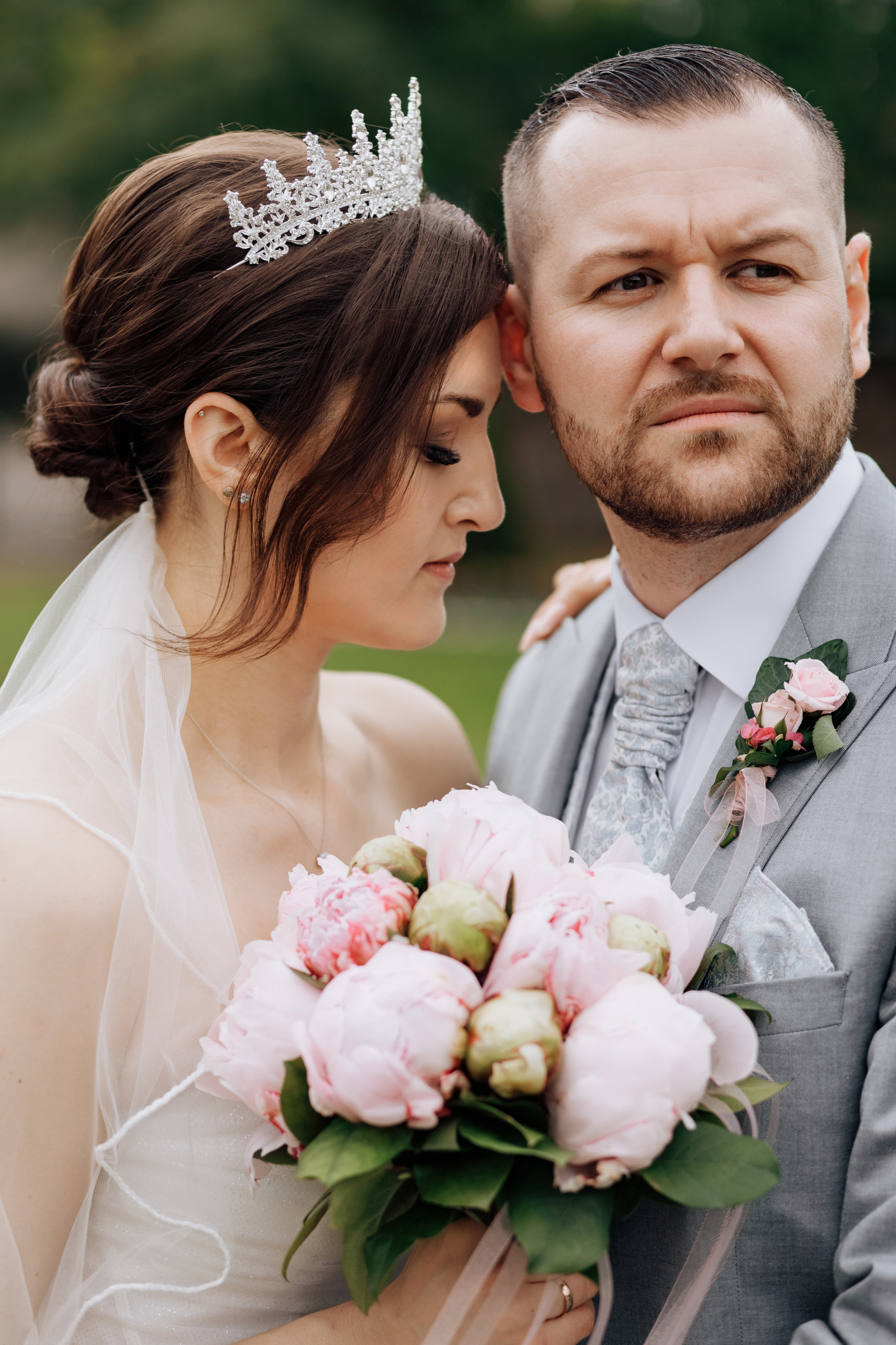 Der Bräutigam schaut in die Ferne, während die Braut sich an ihn schmiegt. 