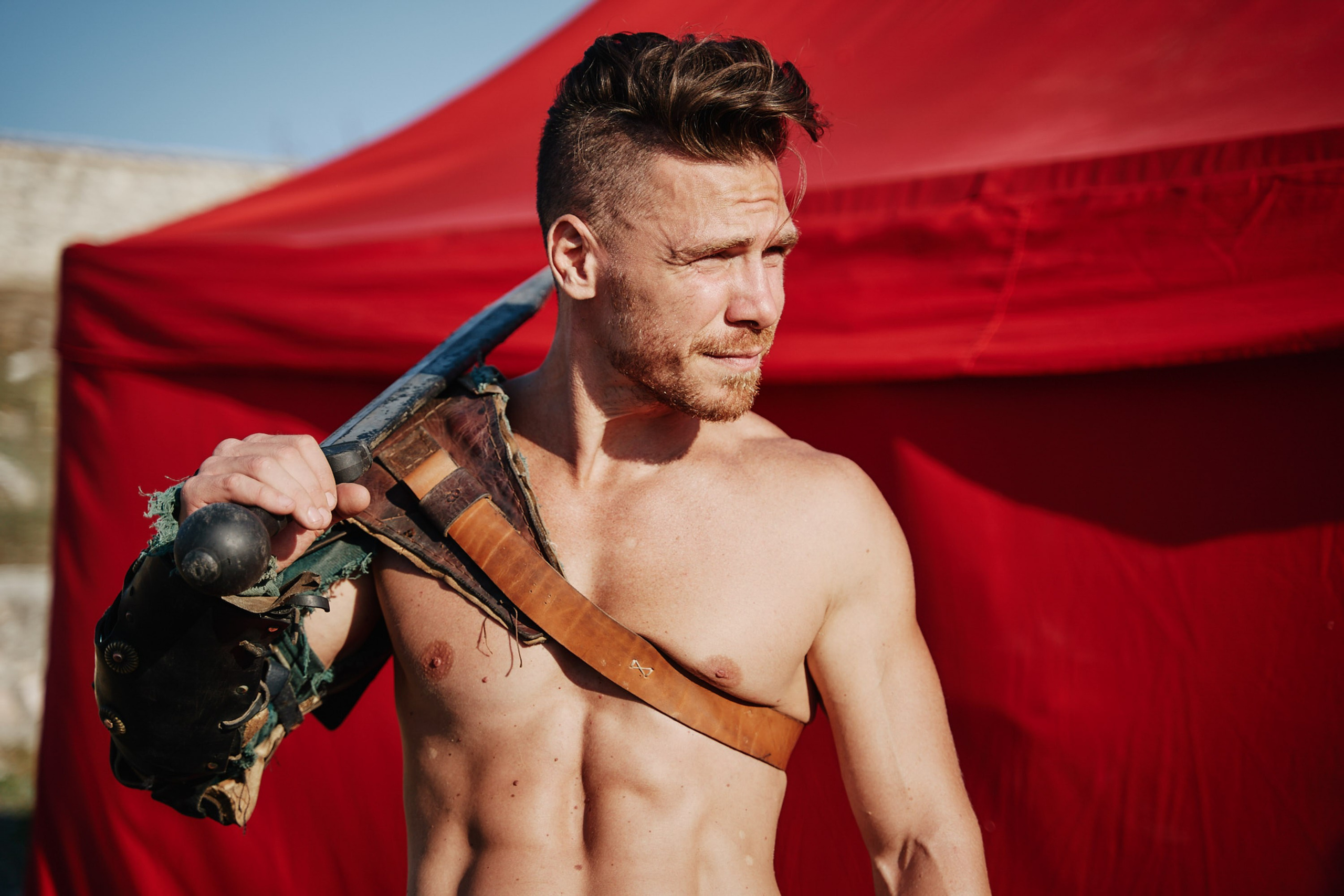 Shirtless man with sword and red cloth behind
