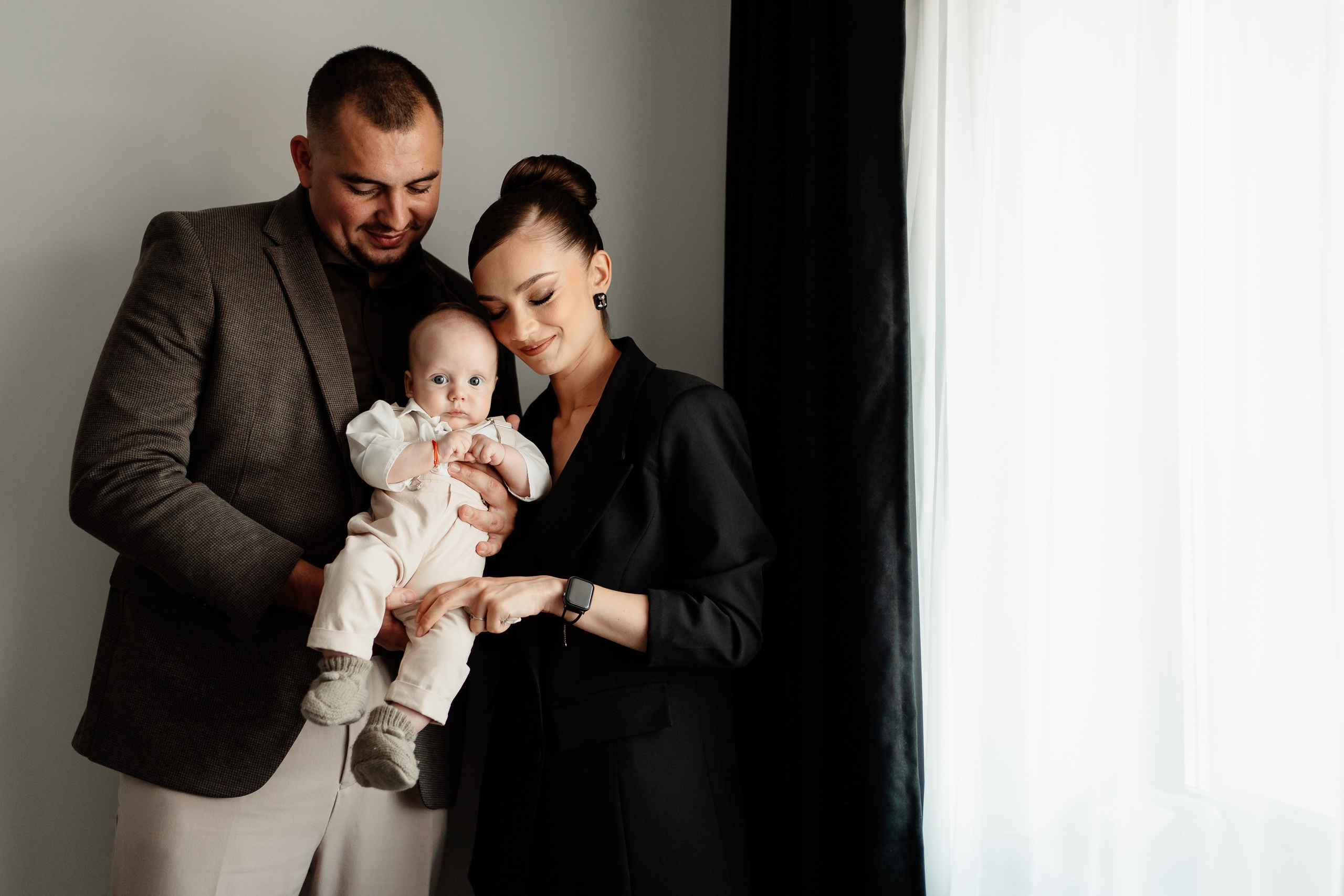 Instantaneu plin de tandrețe dintre părinți și bebeluș în ziua botezului, realizat în Craiova. Fotografie profesională de botez, capturând emoțiile autentice ale familiei într-un decor luminos și cald