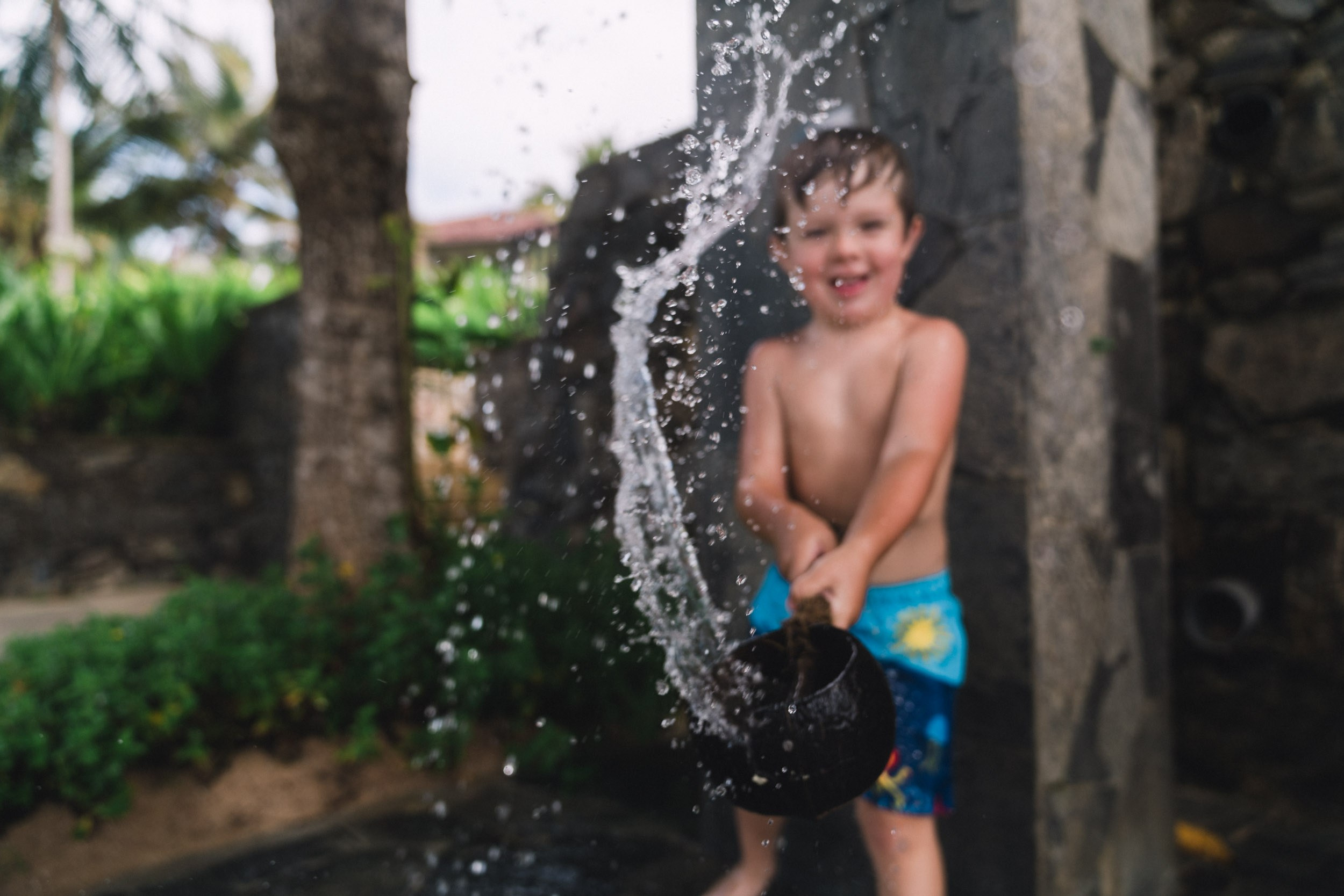 Boy playing with water trying to shower the photographer