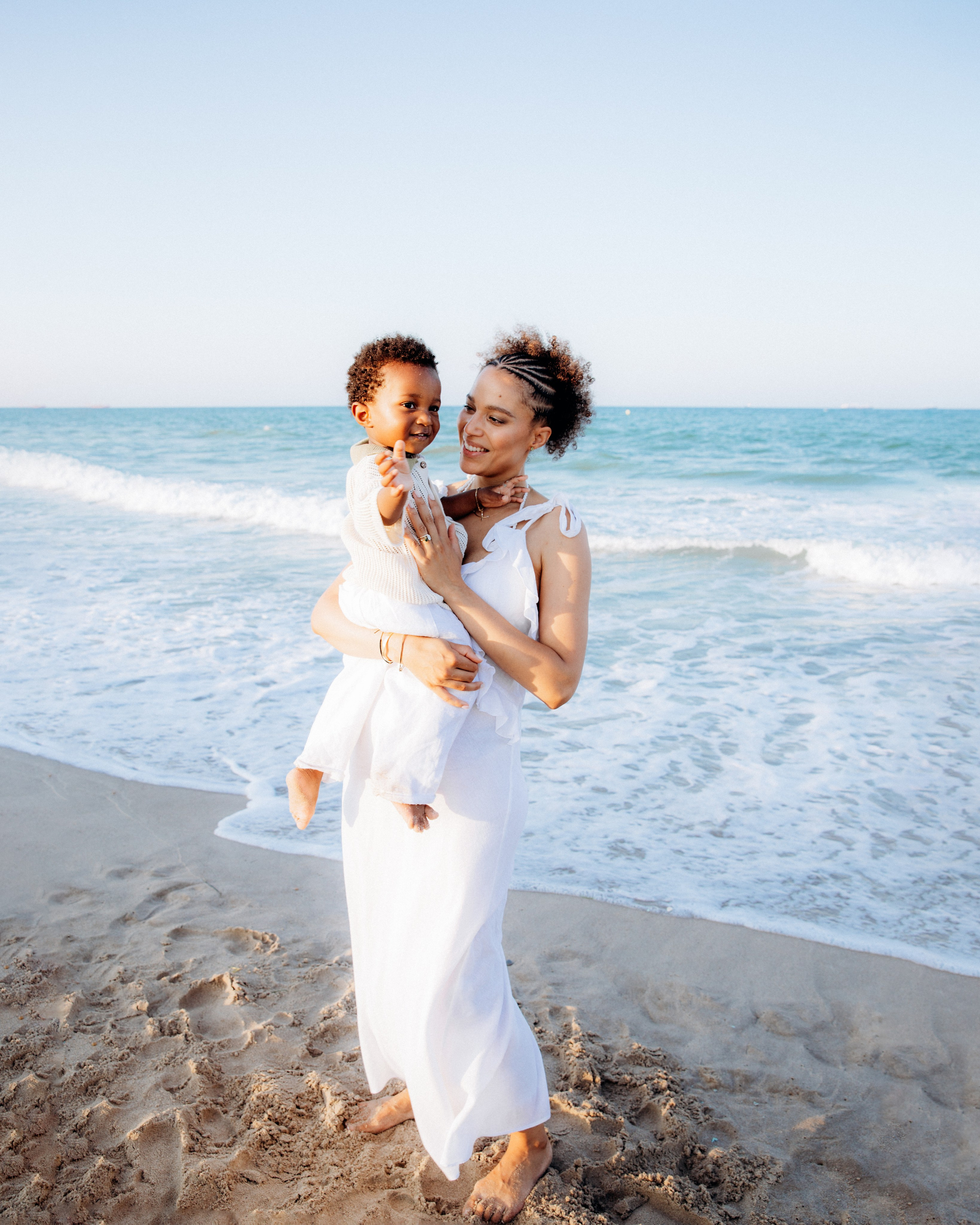 Sesión fotográfica de madre e hijo en la playa de Calpe, España — momento alegre capturado en la orilla con luz suave y olas tranquilas.