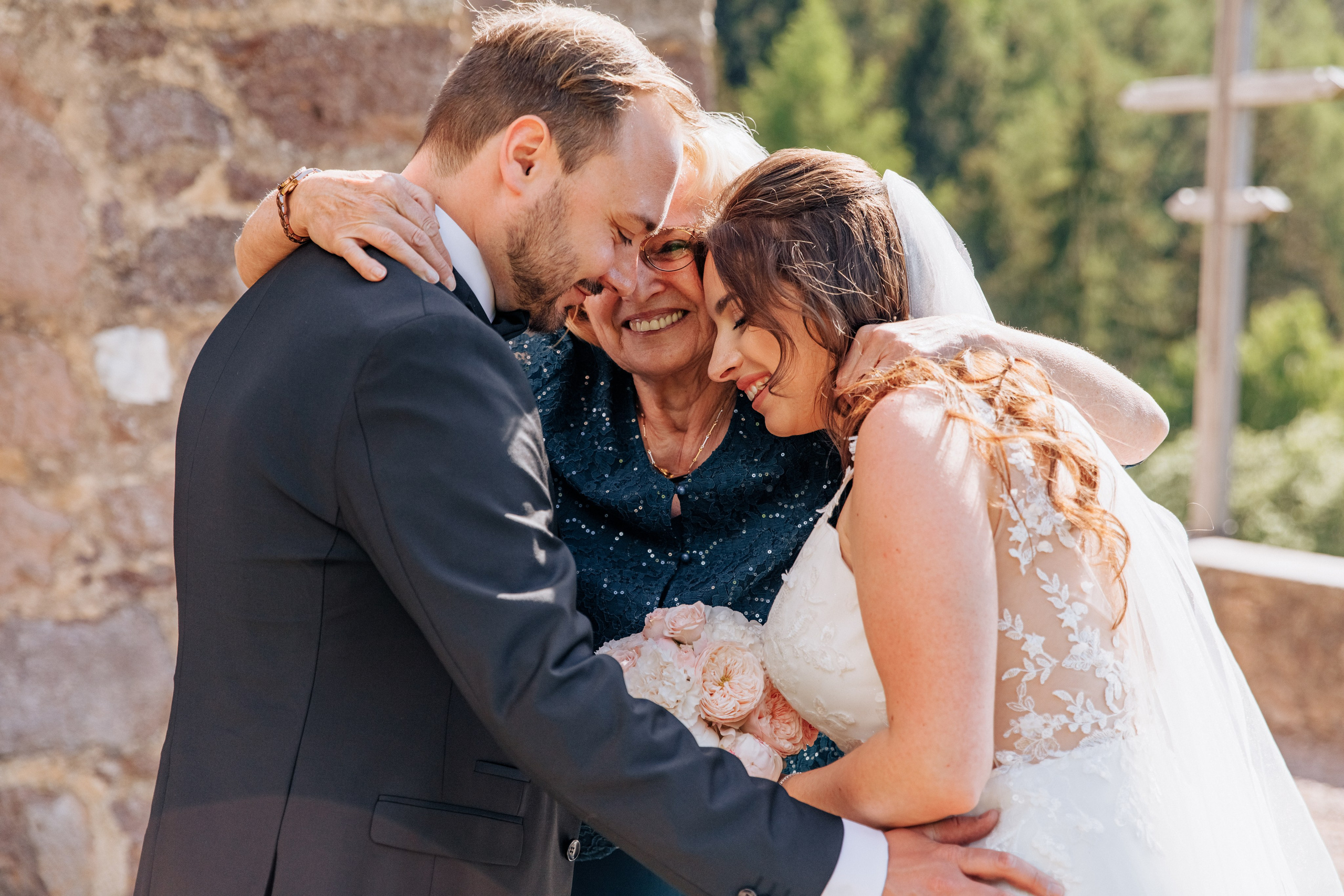 Die Mutter des Bräutigams umarmt das frisch verheiratete Paar nach der Zeremonie.