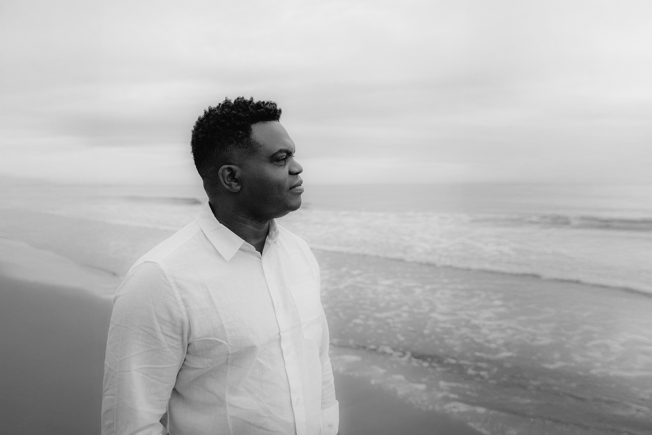 Мужская портретная фотосессия в Валенсии, Испания, с чёрно-белым профильным портретом уверенного мужчины у Средиземного моря, в белой рубашке, смотрящего на горизонт, снятым при мягком естественном свете с спокойным, вневременным настроением — идеально для мужской портретной фотографии, lifestyle-фотосессий для мужчин, портретов для персонального бренда, художественных чёрно-белых портретов и профессиональных мужских фотосессий в Валенсии и по всей Испании.