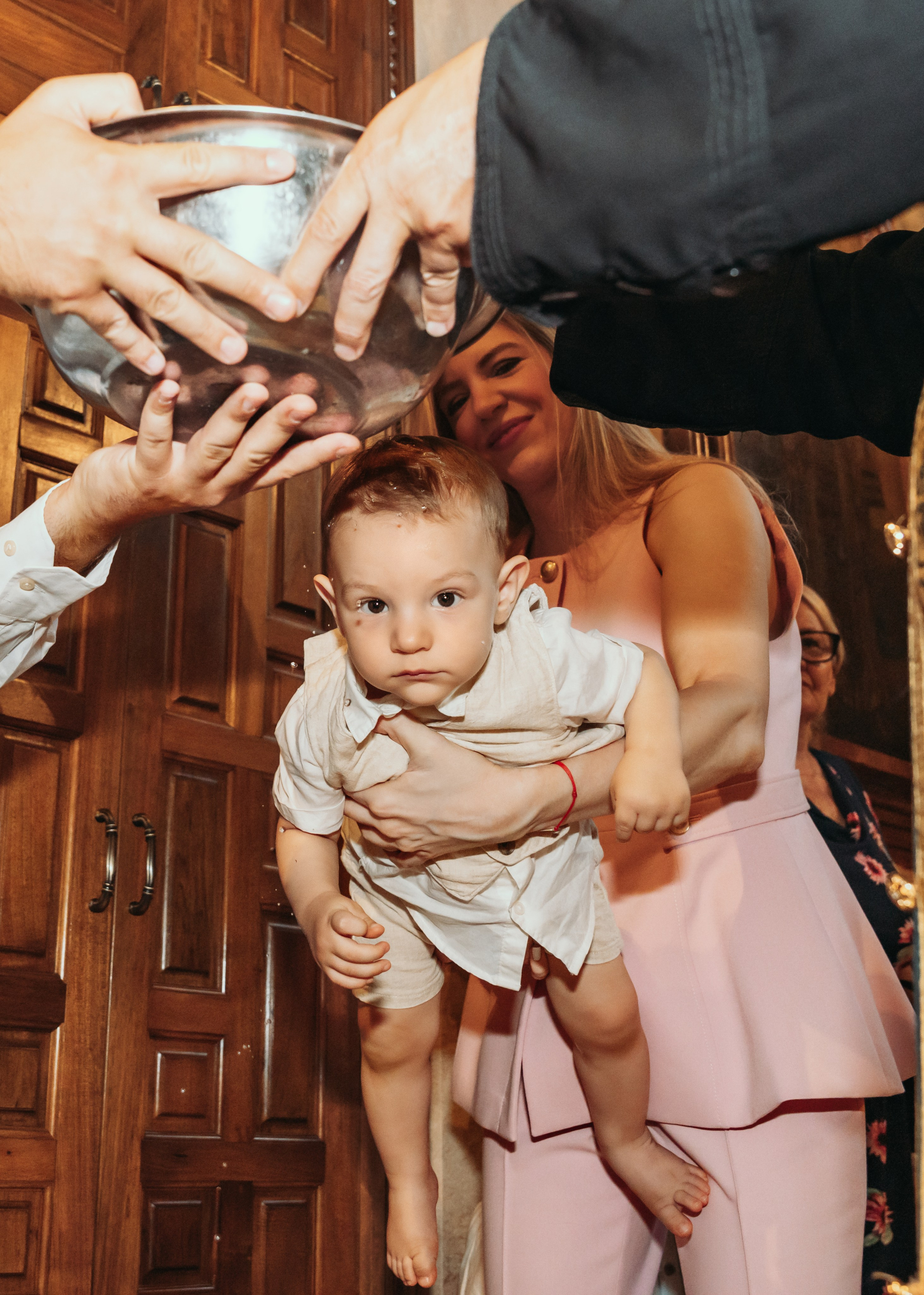 Svestenik poliva decaka u crkvi tokom krstenja