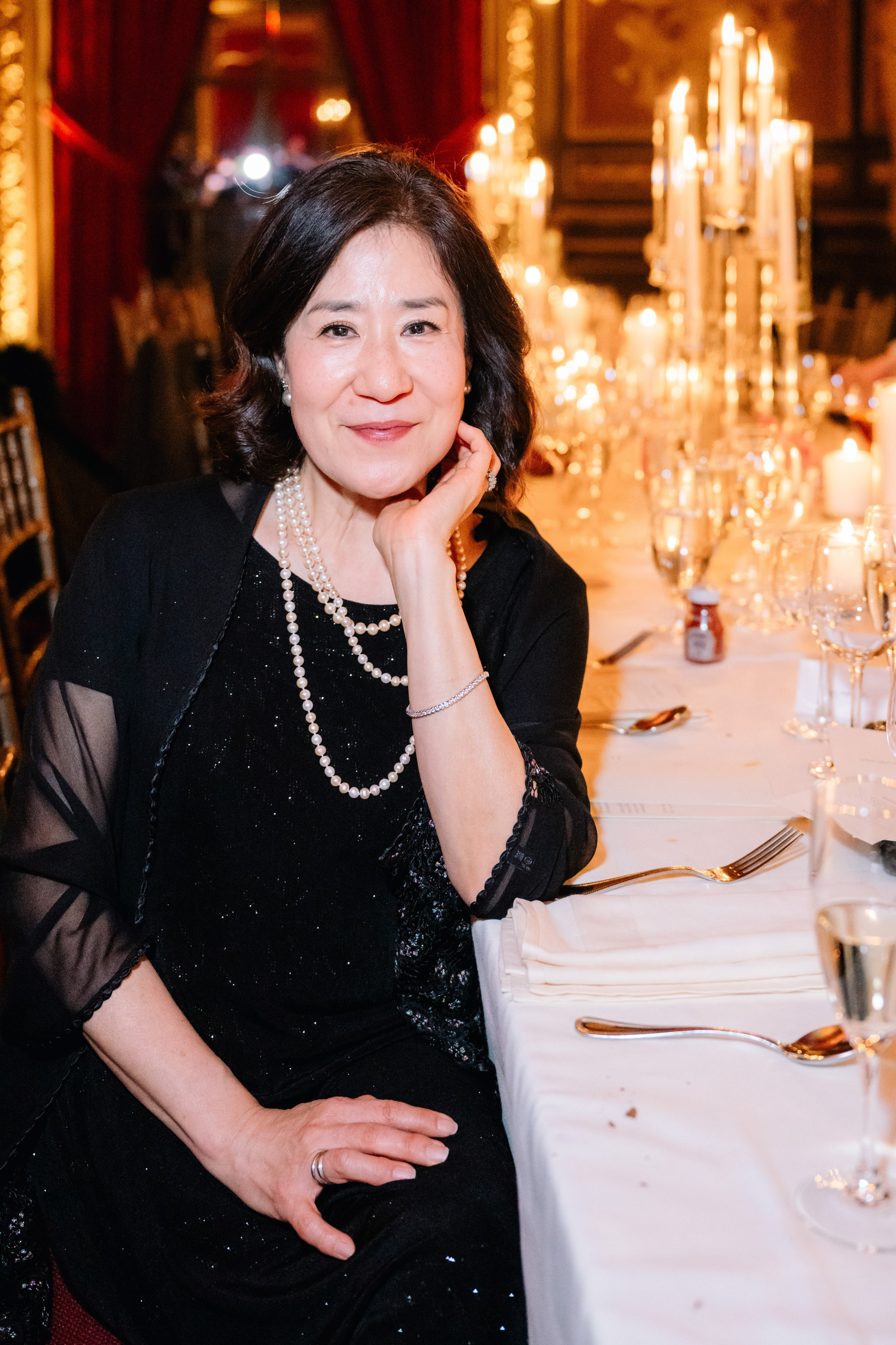 a woman sitting at a table with a candle in her hand