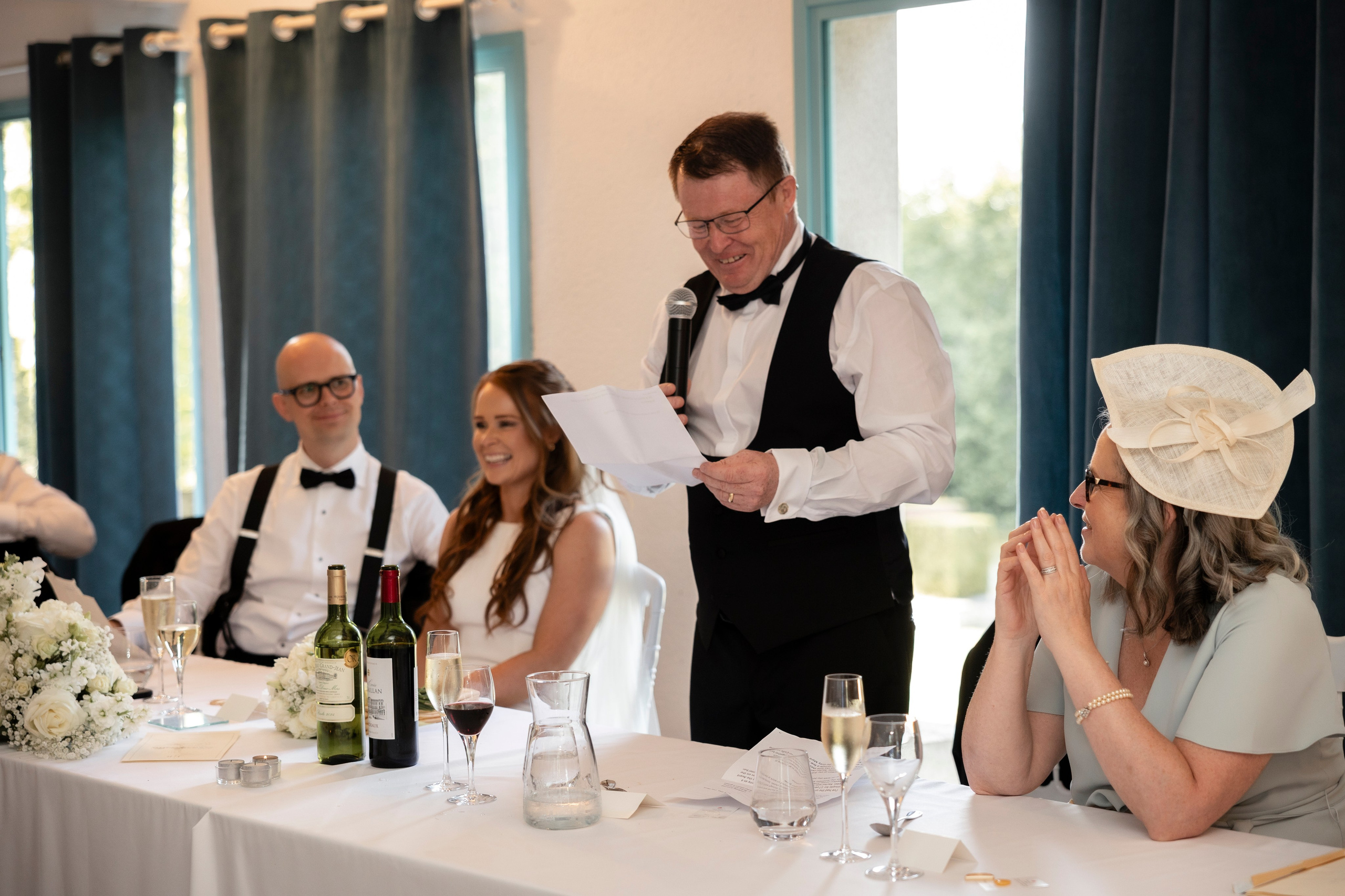  Speech at the wedding meal as guests laugh around the table