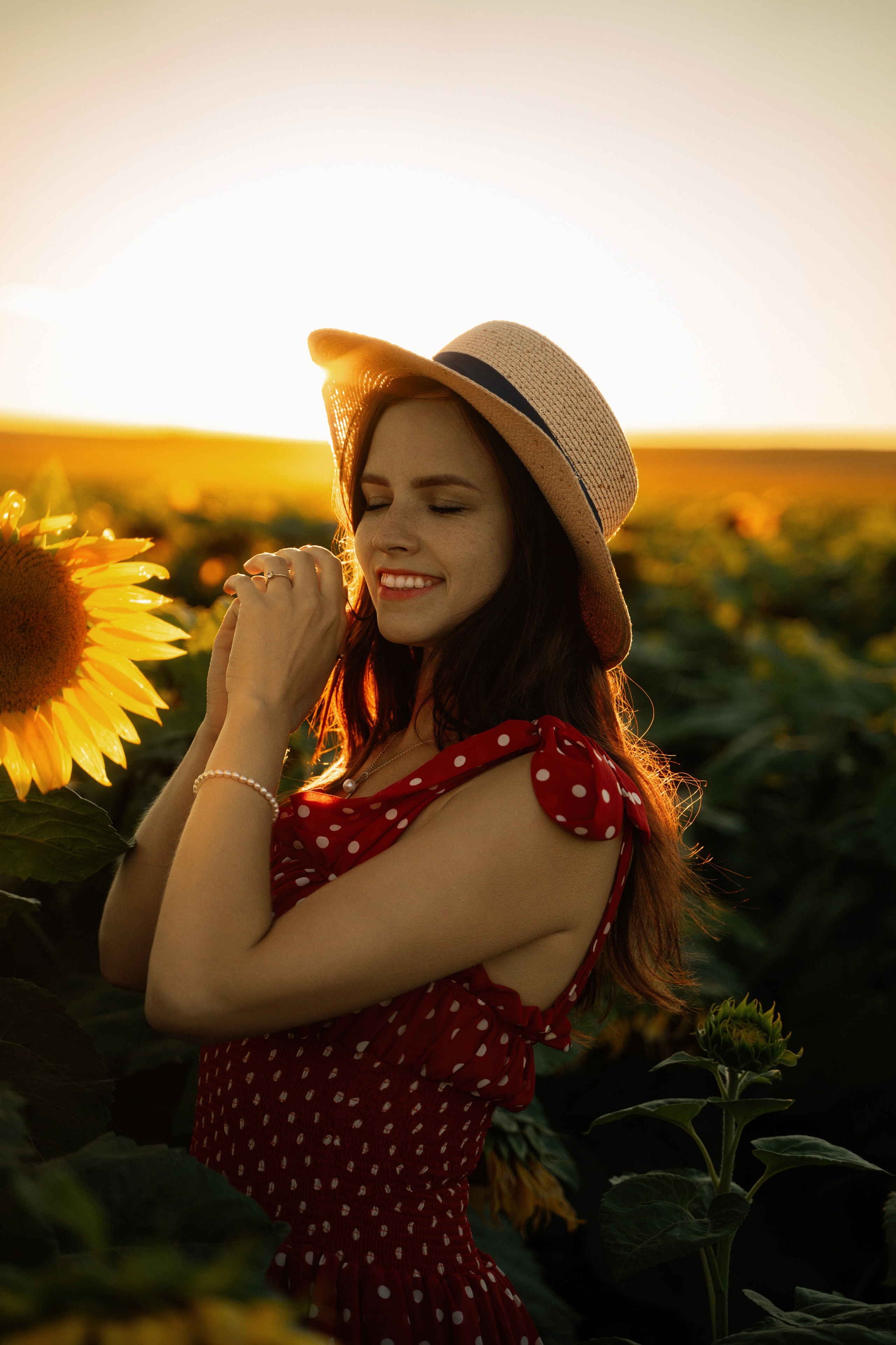 Young beautiful female model posing in a sunflower field at sunset, captured by Marbella portrait photographer