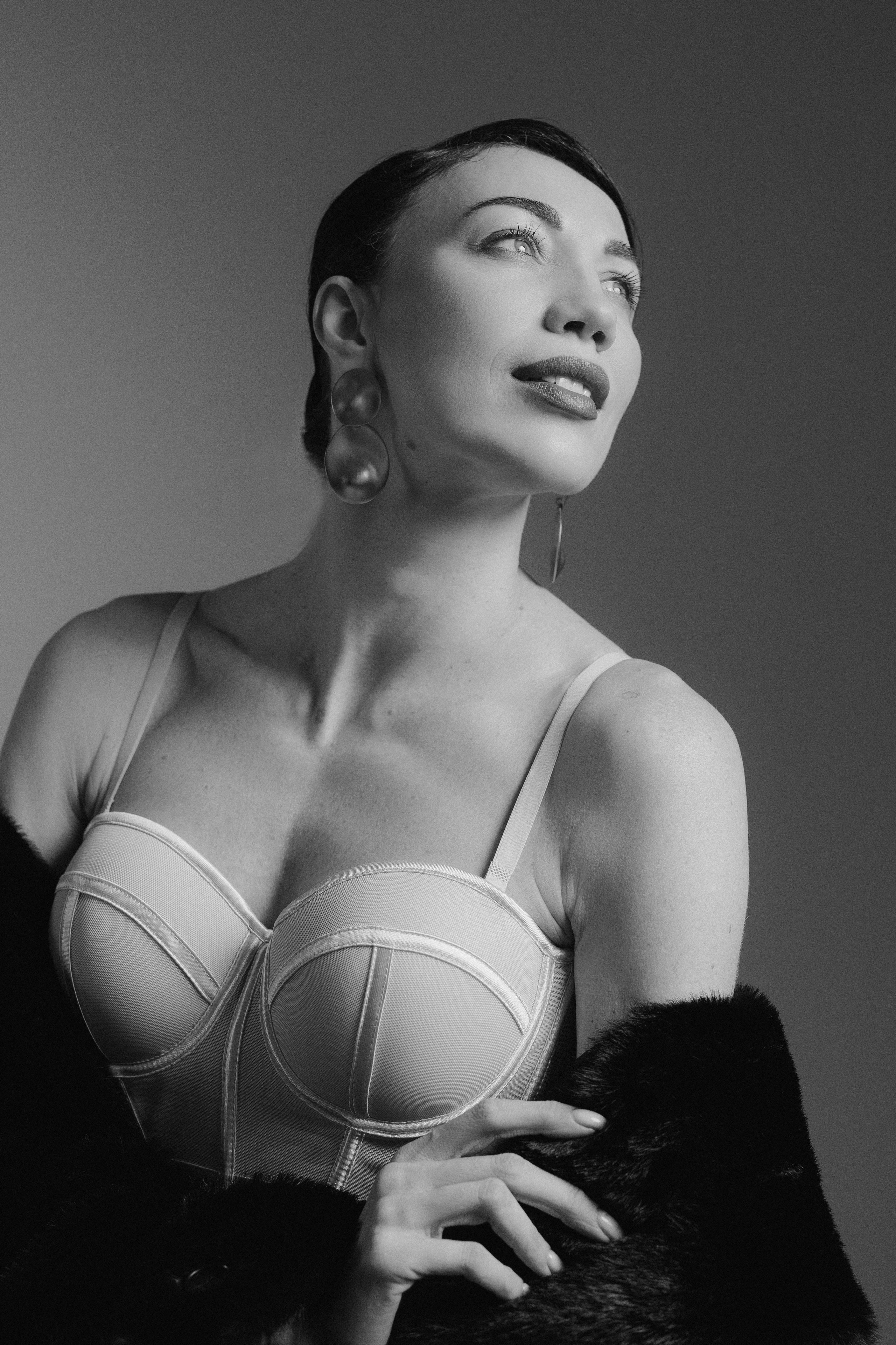 Black and white editorial portrait of a smiling woman with elegant styling and soft studio light, photographed in Leipzig, Germany. Черно-белый редакционный портрет улыбающейся женщины в элегантном образе с мягким студийным освещением, снятый в Лейпциге, Германия.