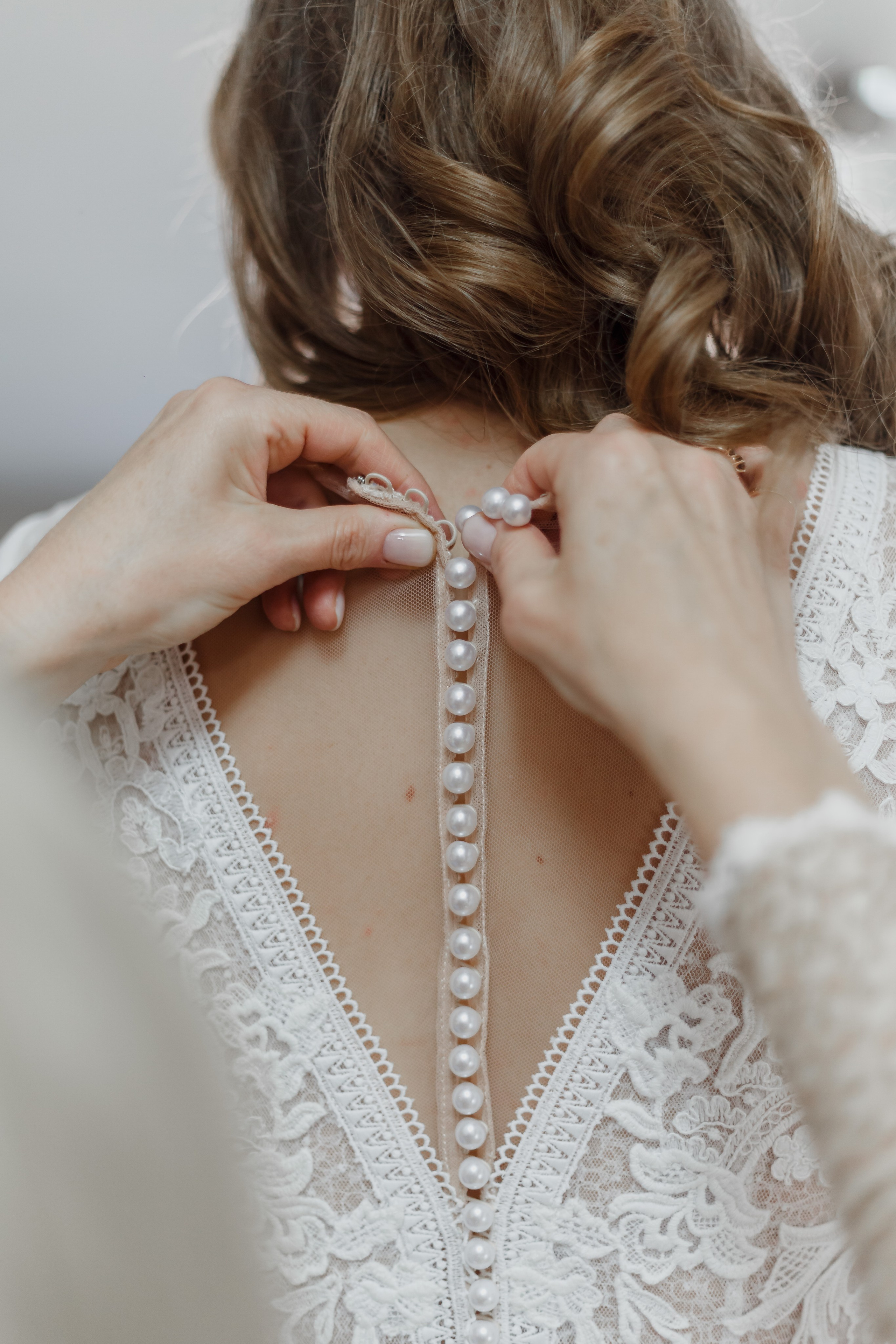 La madre ayuda a la novia a ponerse su vestido de novia