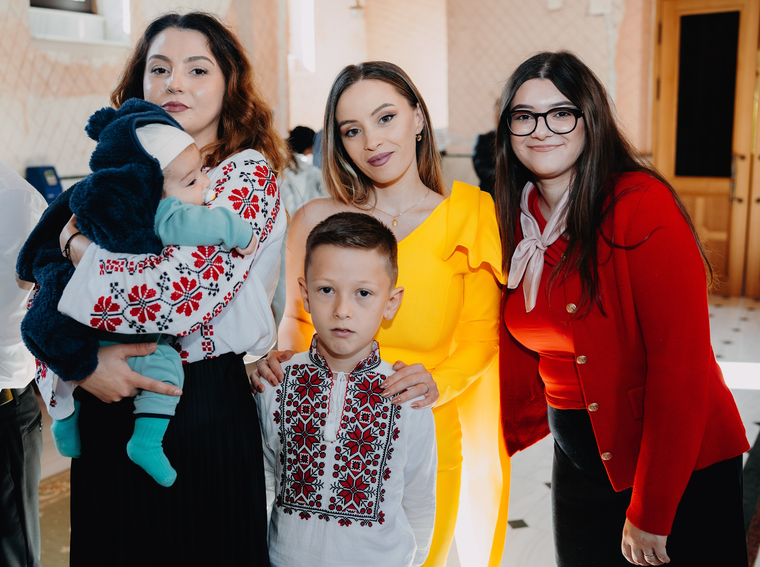 Cadru intim fotografiat din spate: nașa și mama lui Arthur Mihail stau alături, privind amândouă cu reculegere și anticipare spre altarul Catedralei din Bârlad, înainte de botez.