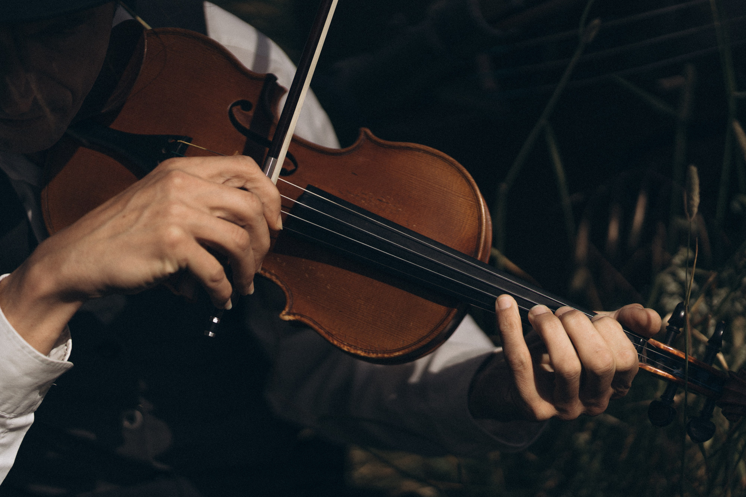 Detailaufnahme, Hände spielen Geige im Sonnenlicht