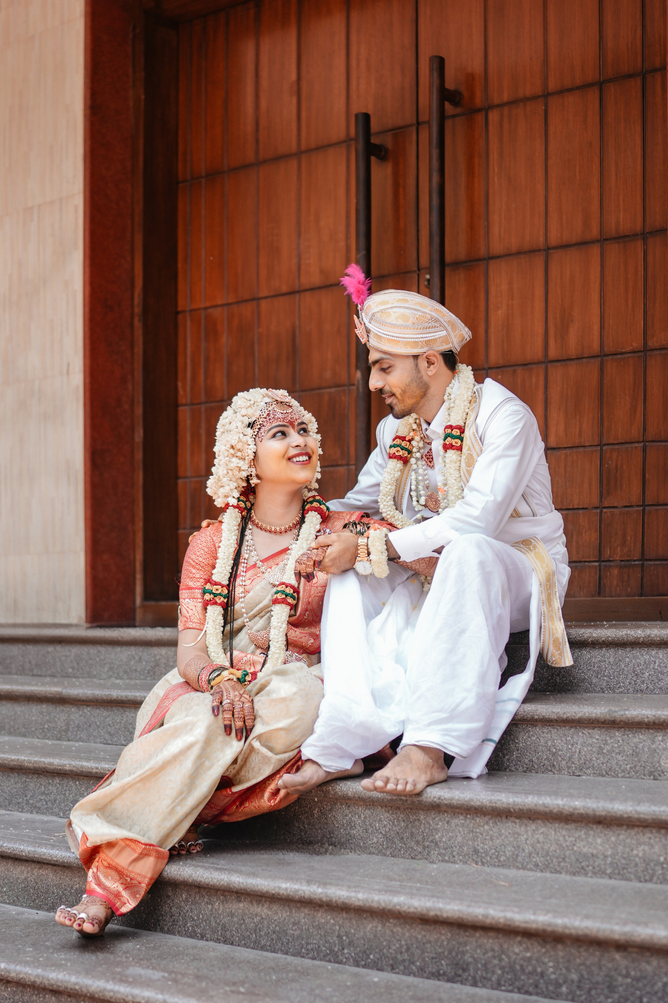 professional candid outdoor portrait of a newly married South Indian couple sitting on stone steps after their wedding in Malleshwaram, Bengaluru