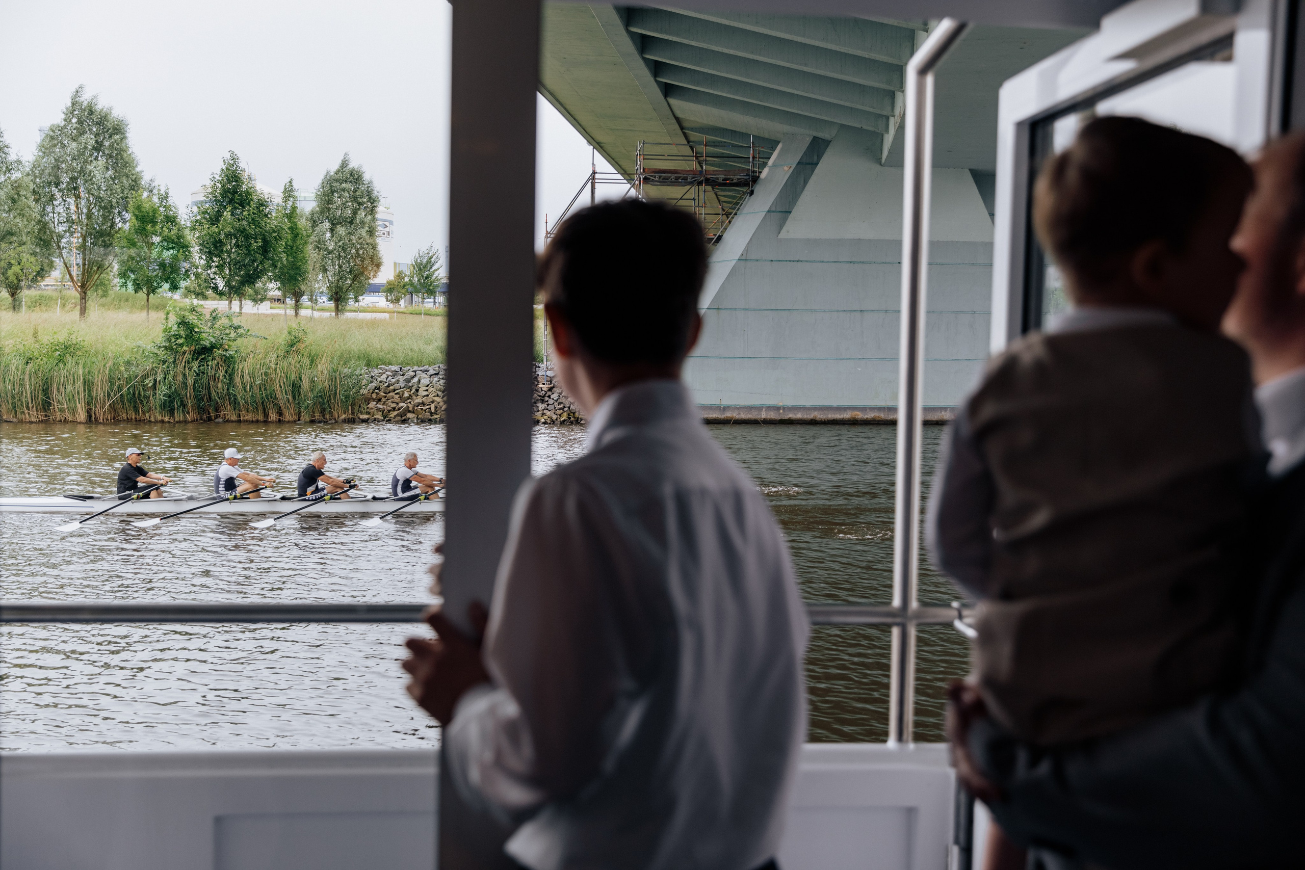 Gäste auf dem Schiff beobachten eine Ruderboot, das vorbeifährt. 