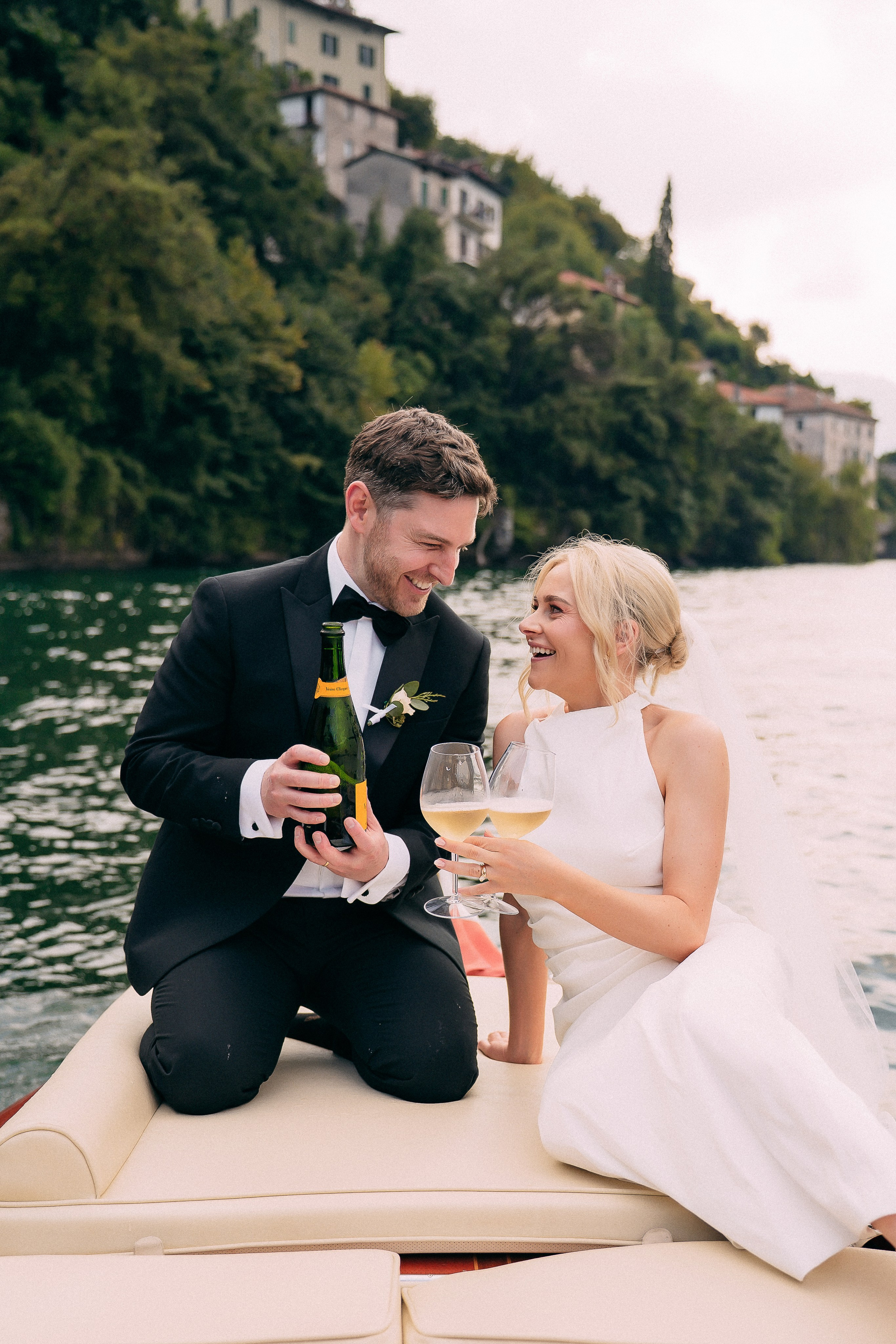 Groom opening champagne on the boat at Villa Lario, Lake Como, Italy