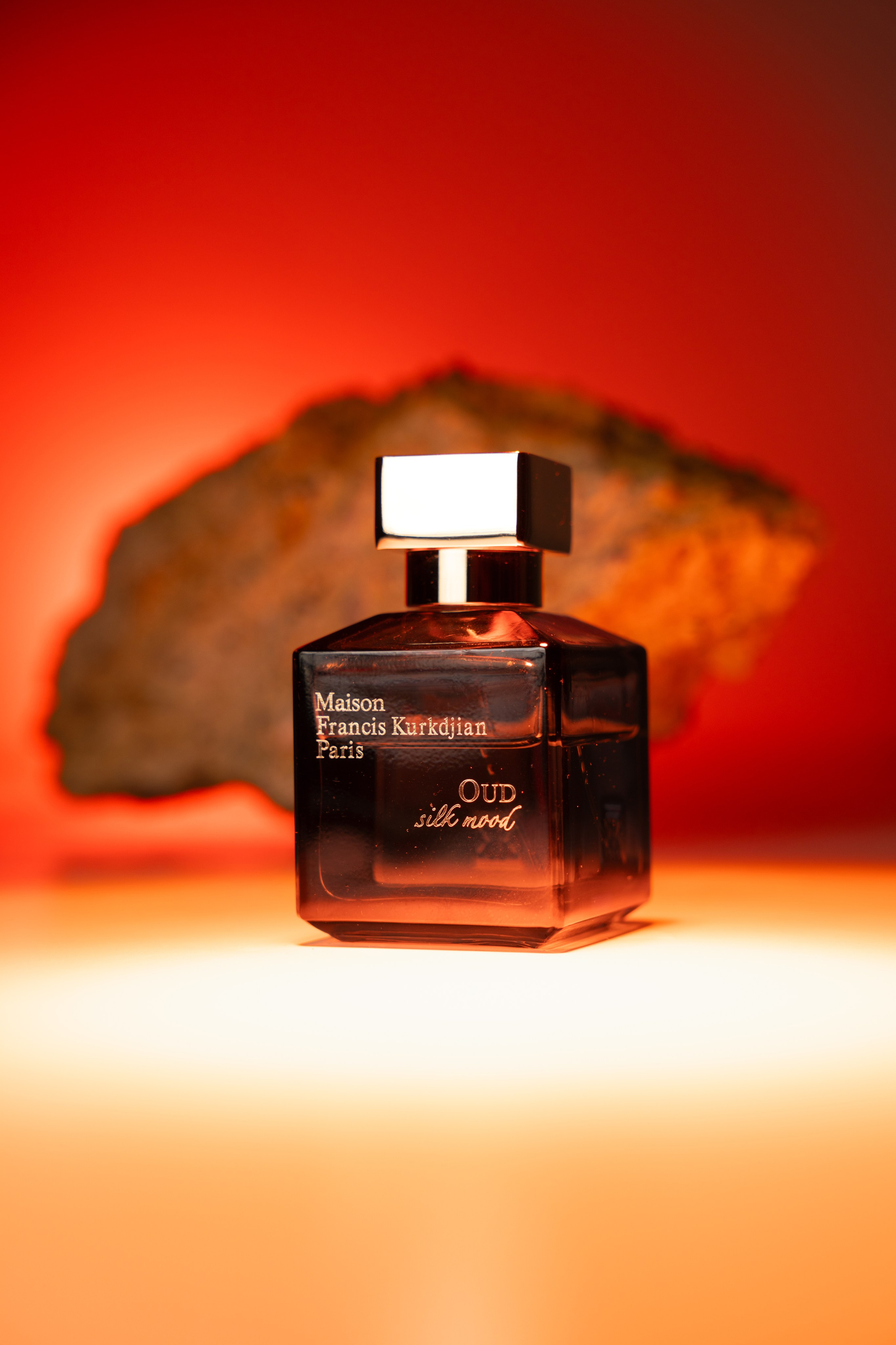 Artistic perfume bottle on red backdrop — bold colour commercial shoot London.