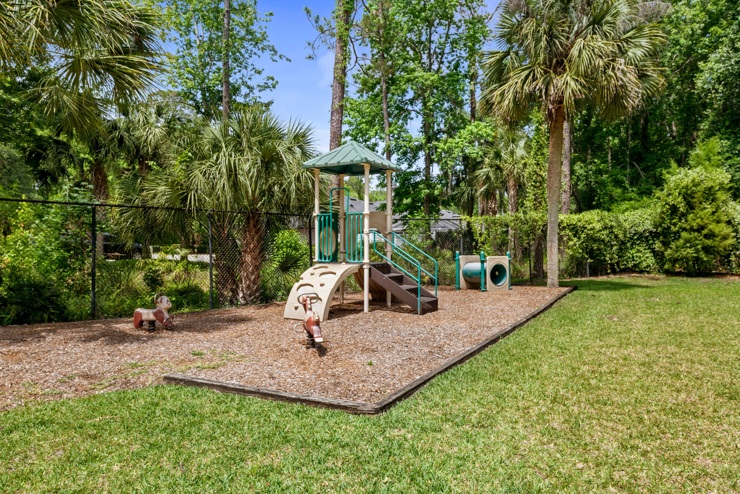 Small playground with mulch ground and tropical landscaping
