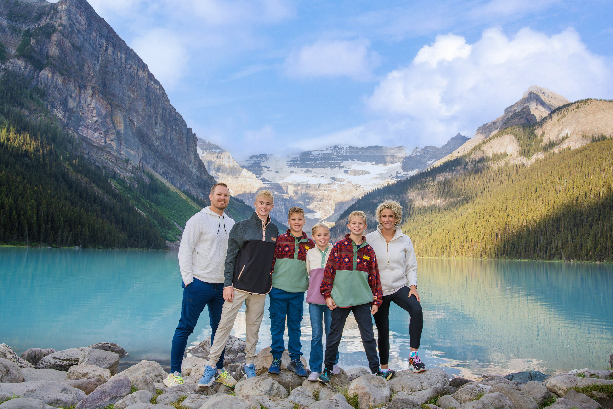 Family of four standing on the shoreline of Lake Louise in Banff, Alberta