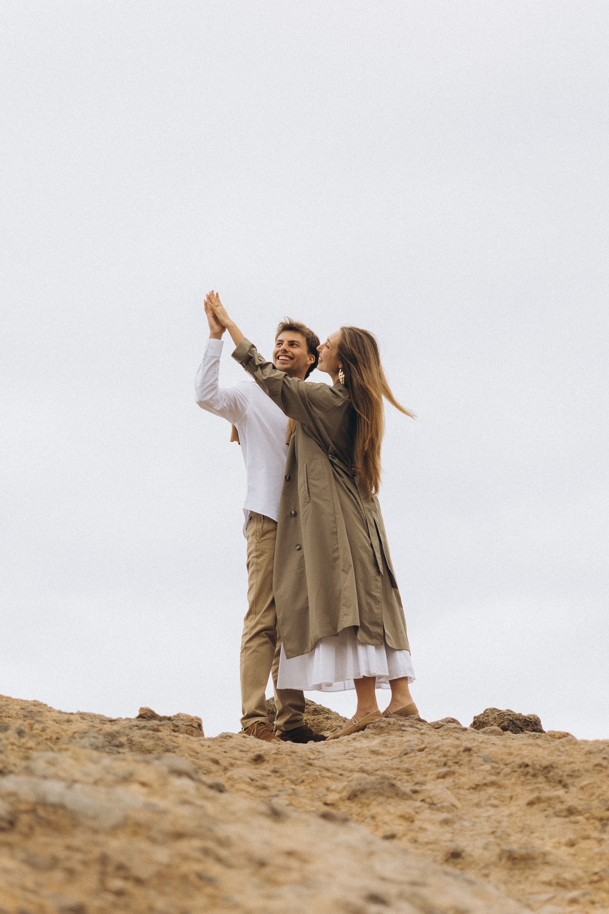 Beautiful engagement moment by the ocean in Madeira, Portugal, as one partner kneels to propose while waves crash in the background.