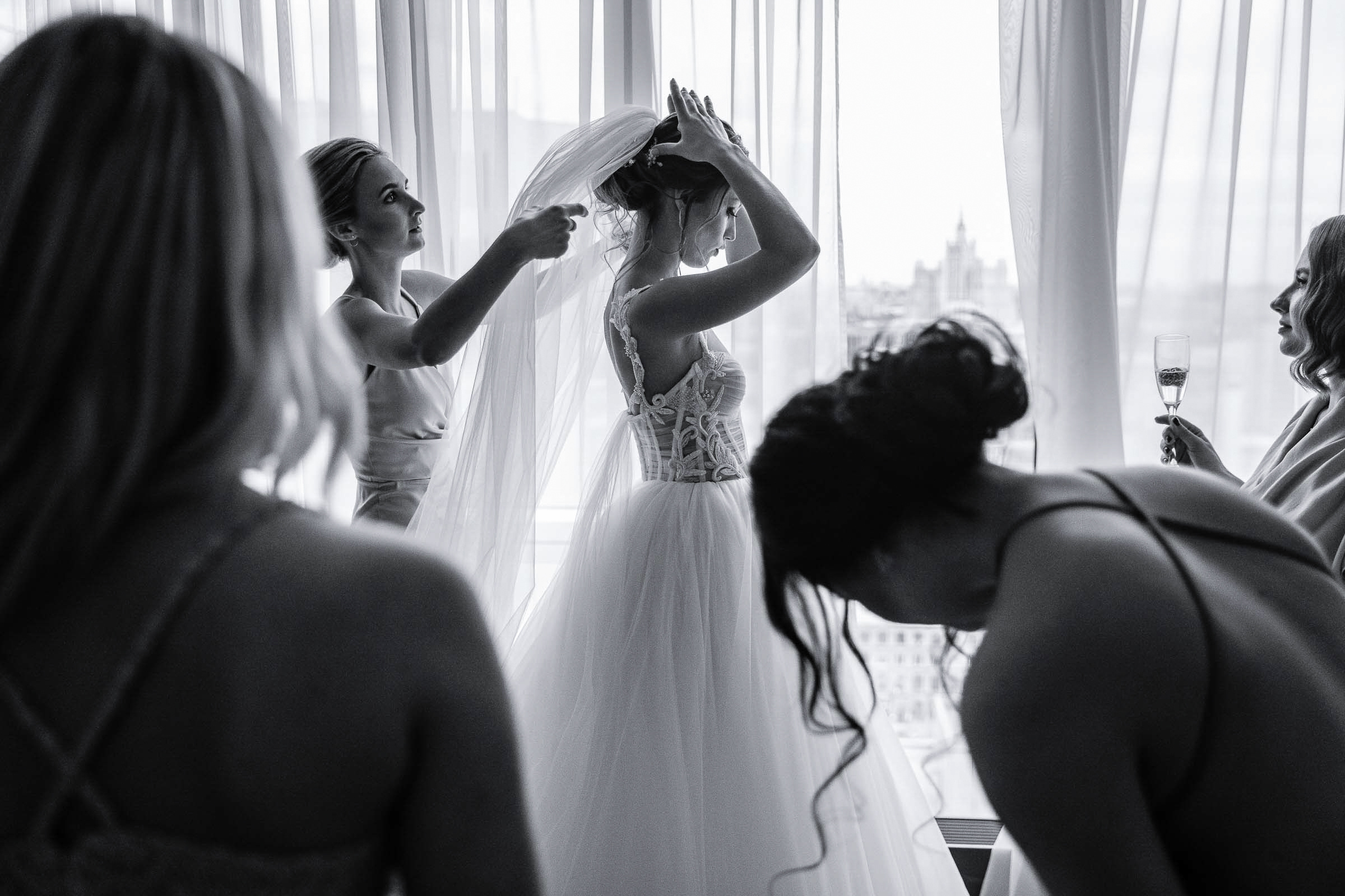 Bride fixing veil by window, by Tanya Bodgan, Bude wedding photographer.  