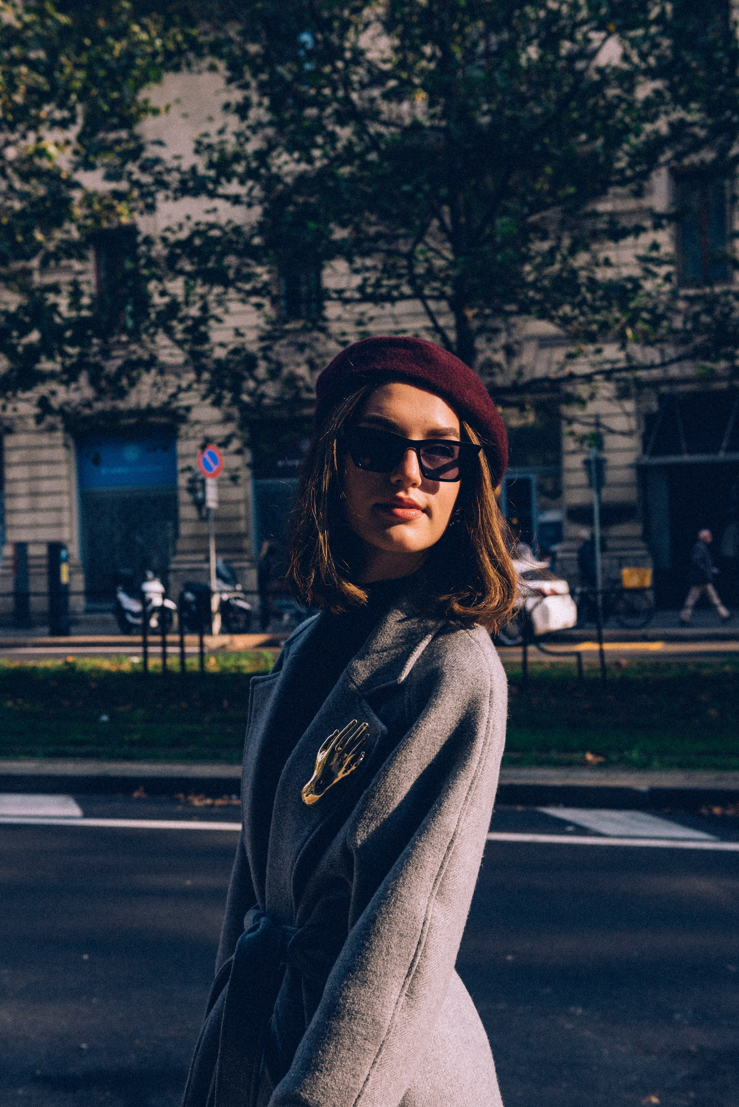 Artistic street photography in Milan: a fashionable woman framed by dramatic shadows and sunlight, showcasing refined style and urban charm. Emotional storytelling photographer in Milan