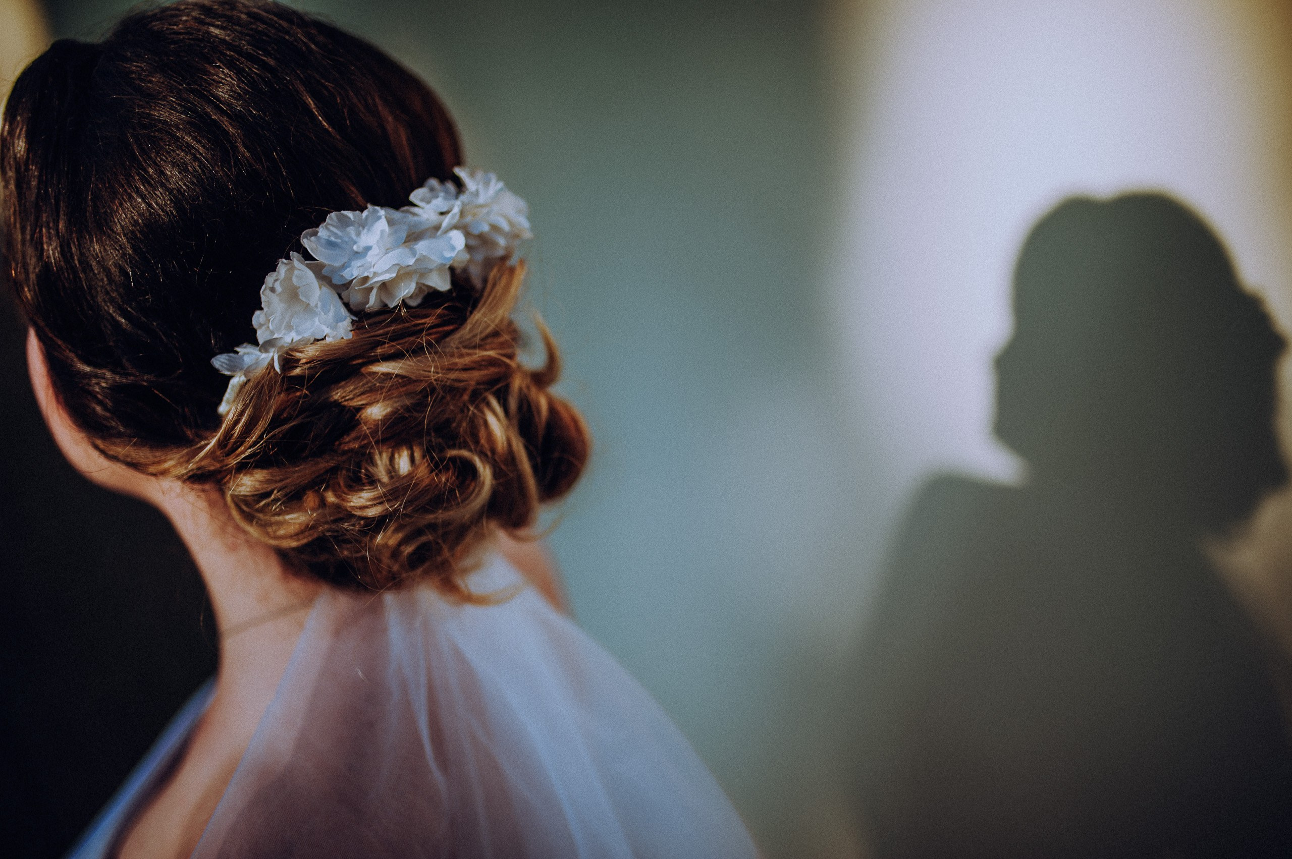 Un portret fără privire spre cameră: cocul cu flori și umbra profilului alcătuiesc compoziția. Cătălina și Nicu — ședință foto after wedding, portofoliul Photosinteza, Cluj-Napoca.