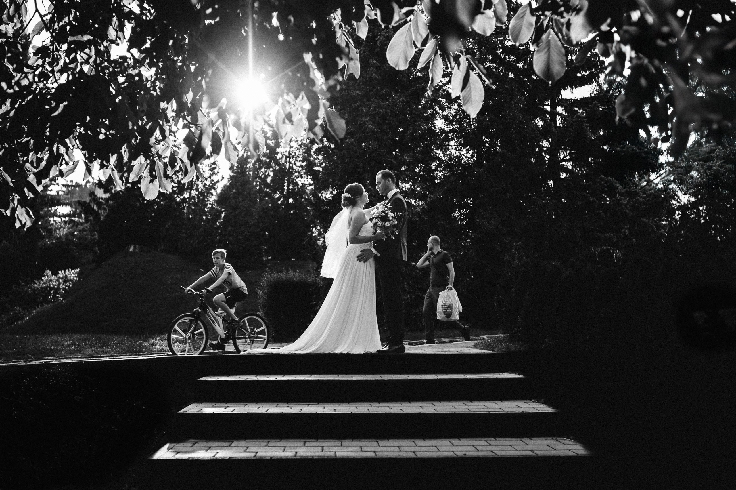 Un cadru larg în alb-negru, în care portretul de cuplu se întâlnește cu mișcarea din parc. Cătălina și Nicu — ședință foto after wedding, portofoliul Photosinteza, Cluj-Napoca.