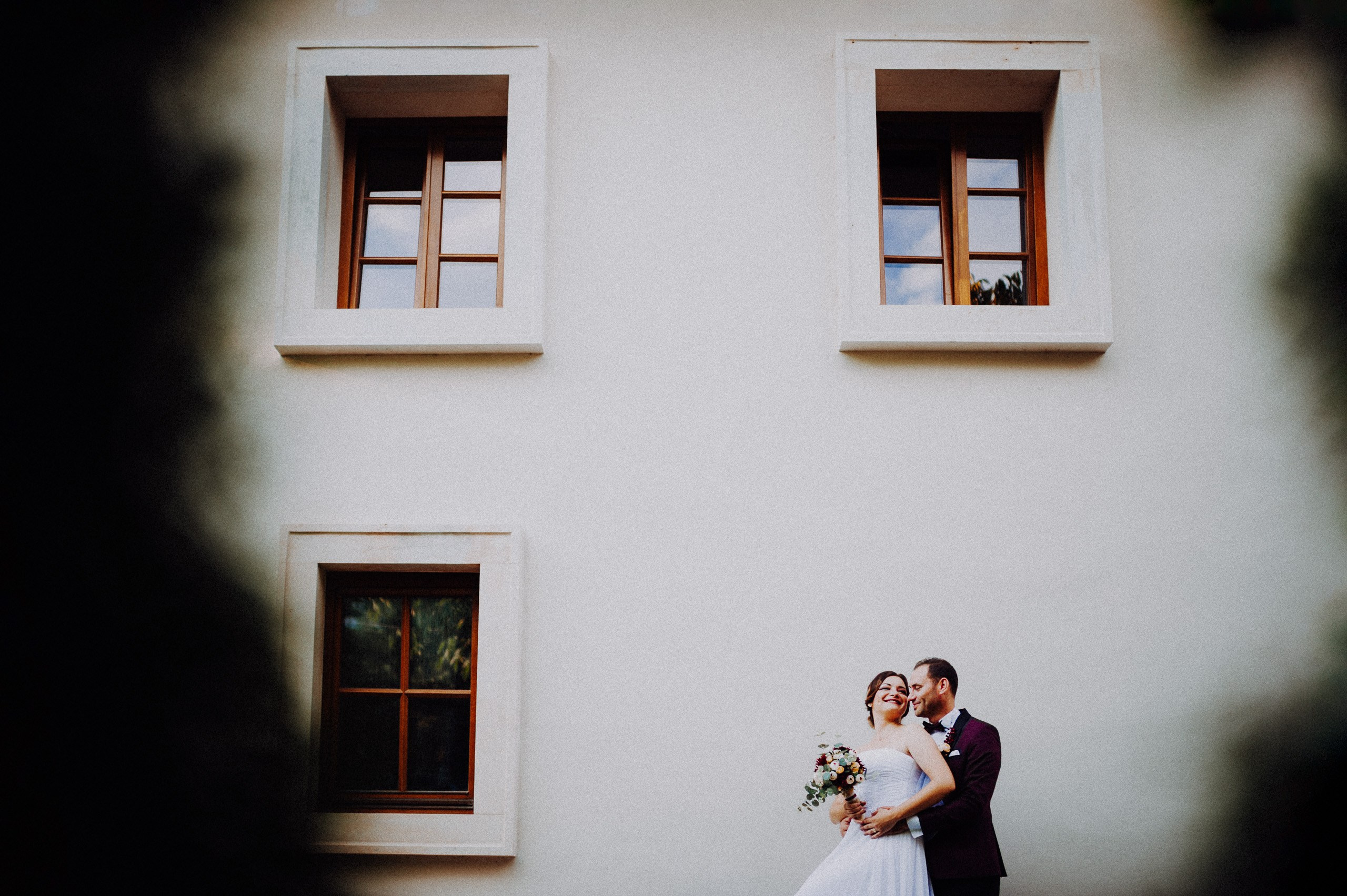 O compoziție urbană cu mult spațiu liber, ferestre din lemn și cuplul așezat în colțul cadrului. Cătălina și Nicu — ședință foto after wedding, portofoliul Photosinteza, Cluj-Napoca.