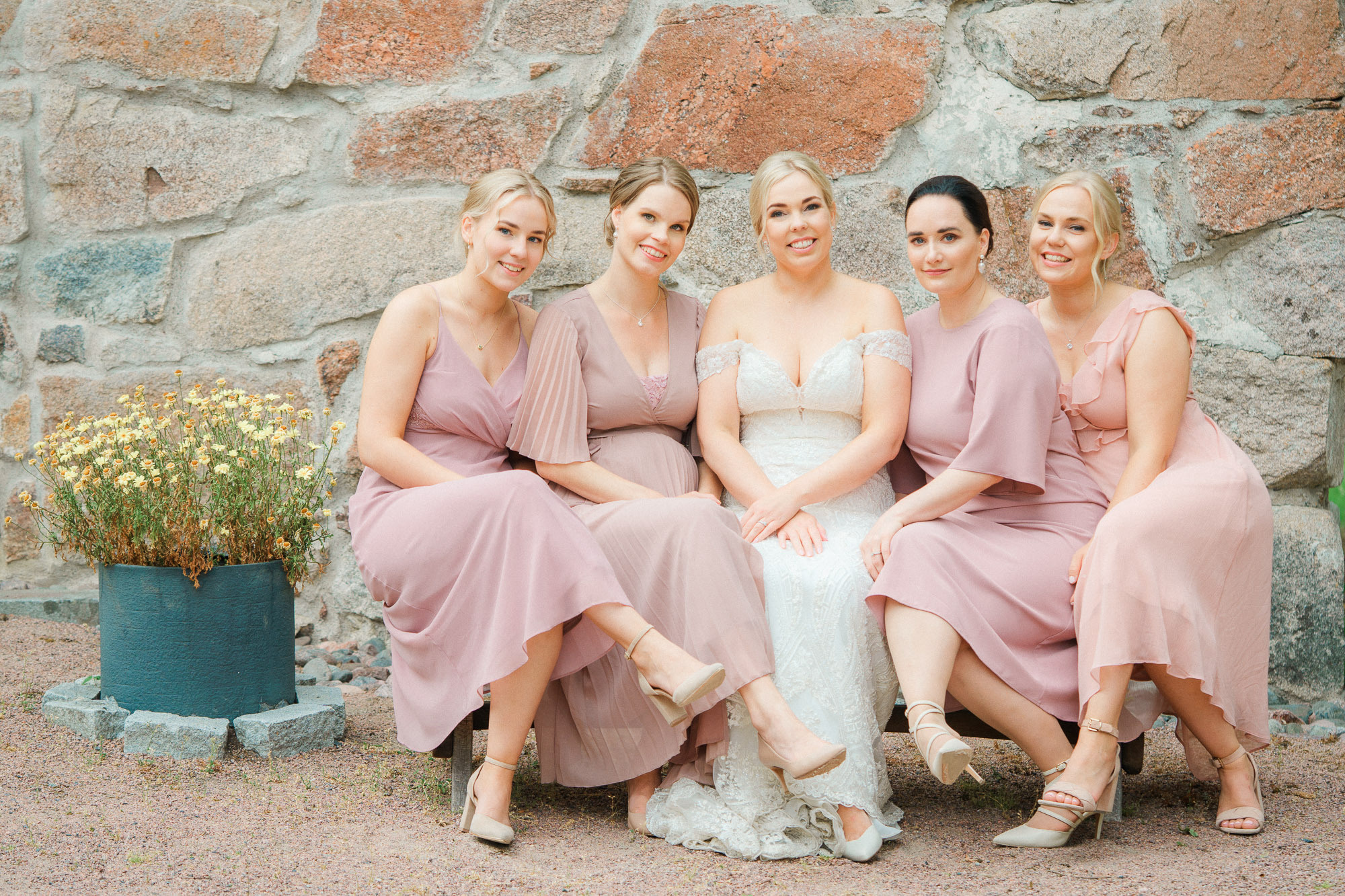 Morsian ja kaasot istuvat penkillä