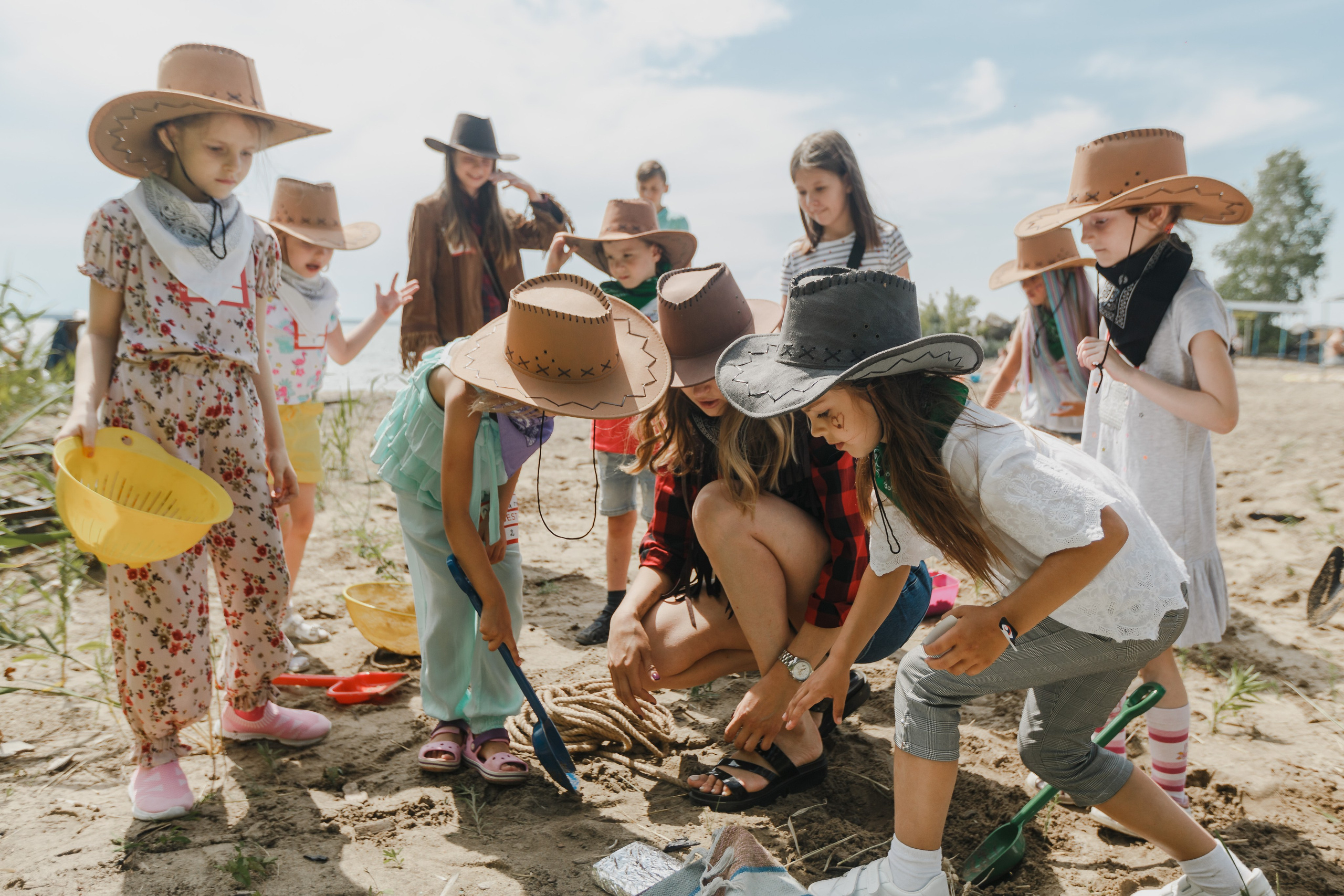 Un equipo de niños vestidos con sombreros busca un tesoro en la orilla del mar