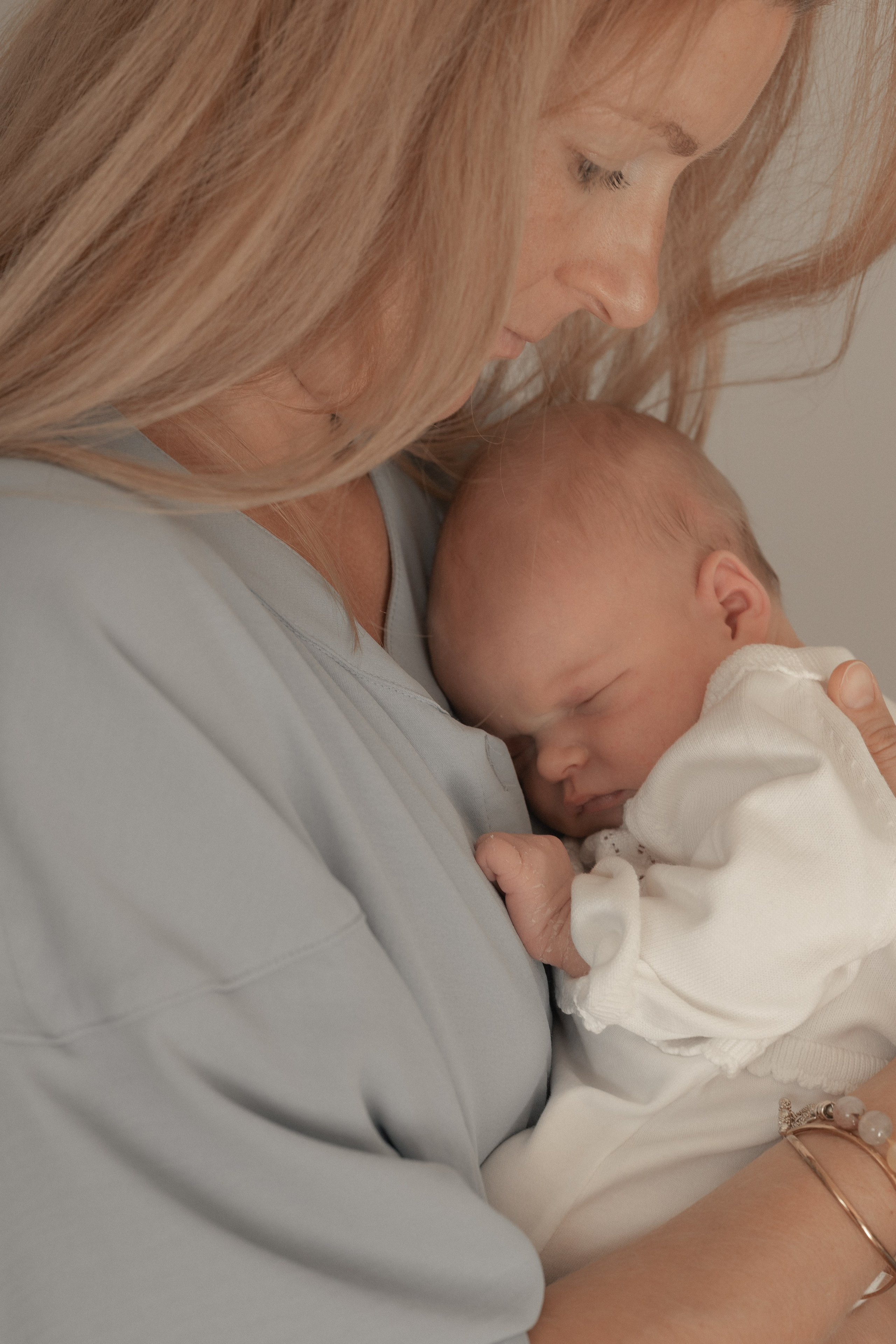 Mutter hält ihr Neugeborenes sanft im Arm – inniger Moment während eines Baby-Fotoshootings in Salzburg