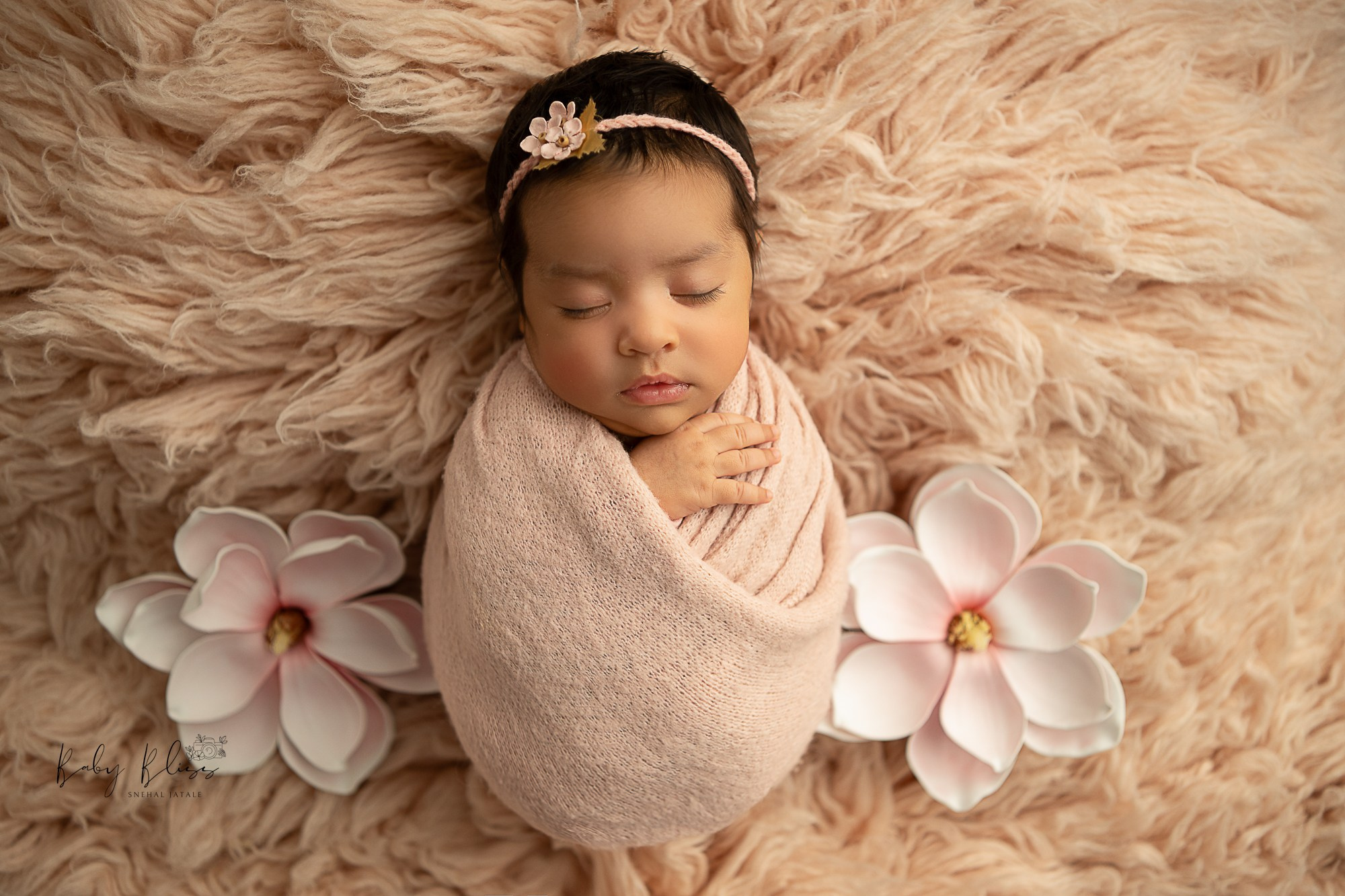 pastel soft pink colour flokati fur is used in the background, newborn baby girl is sleeping peacefully.