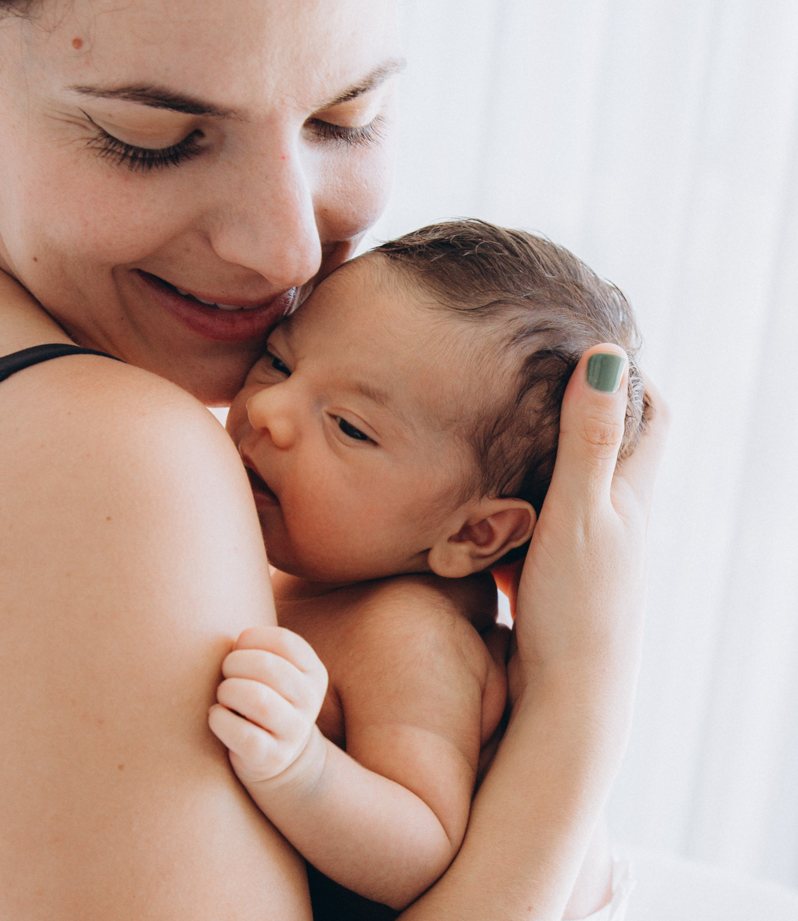 Primer plano de una madre abrazando tiernamente a su bebé recién nacido en Alicante, España — momento de amor maternal ideal para sesiones de recién nacido y familia en el sur de España.