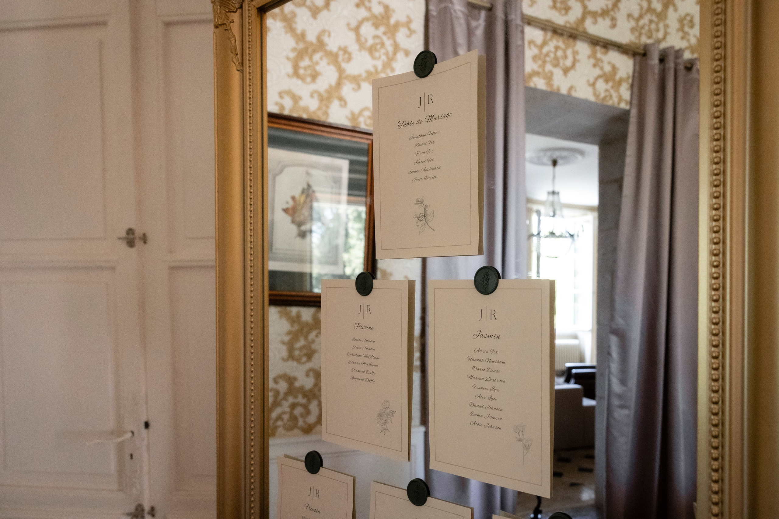 Wedding seating plan cards hanging on a mirror at the château